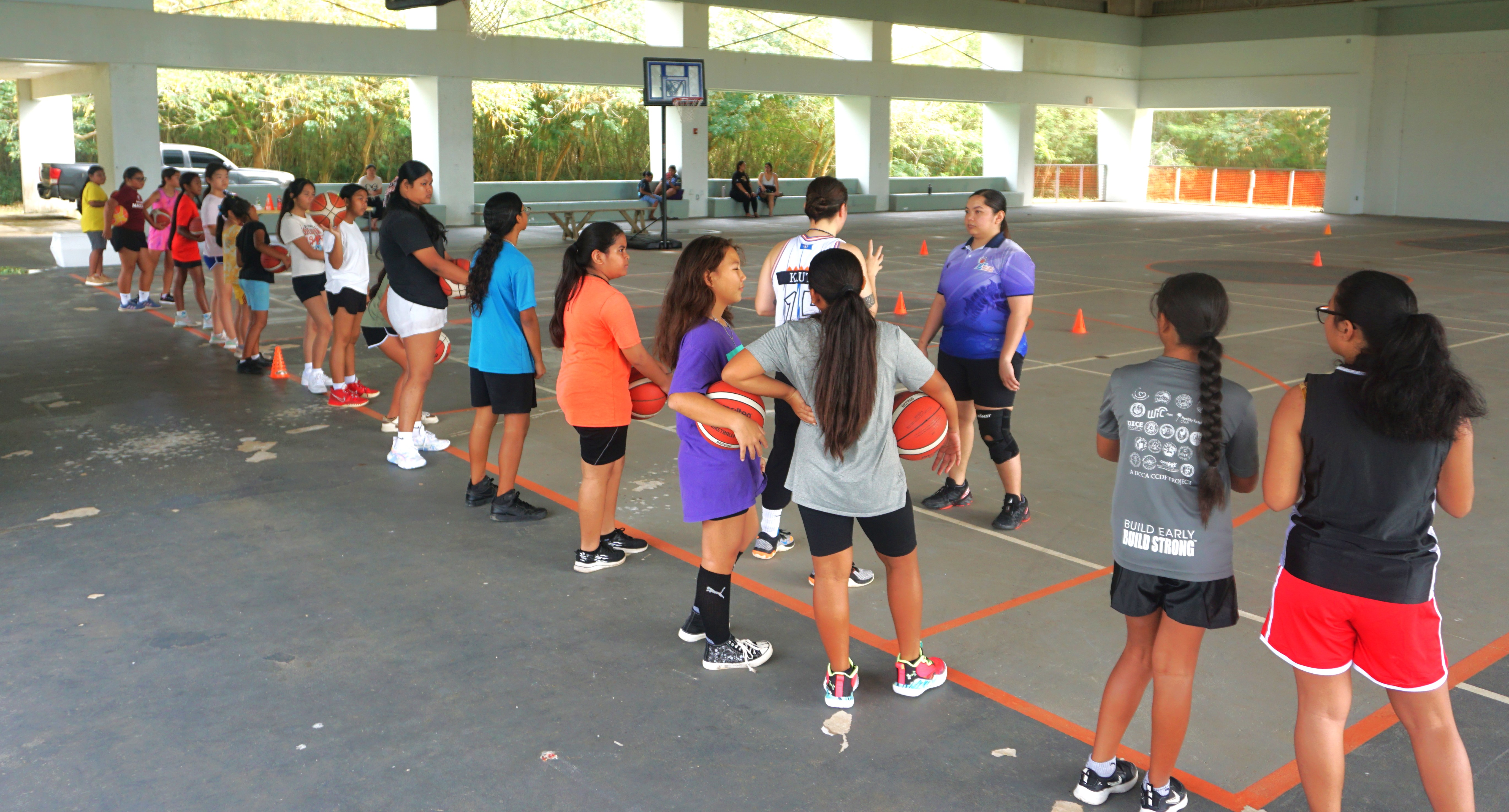 Marlene Lumabi and coach Mikki Kautz with the participants of the I Am Her basketball camp at the Koblerville gym on Saturday.
