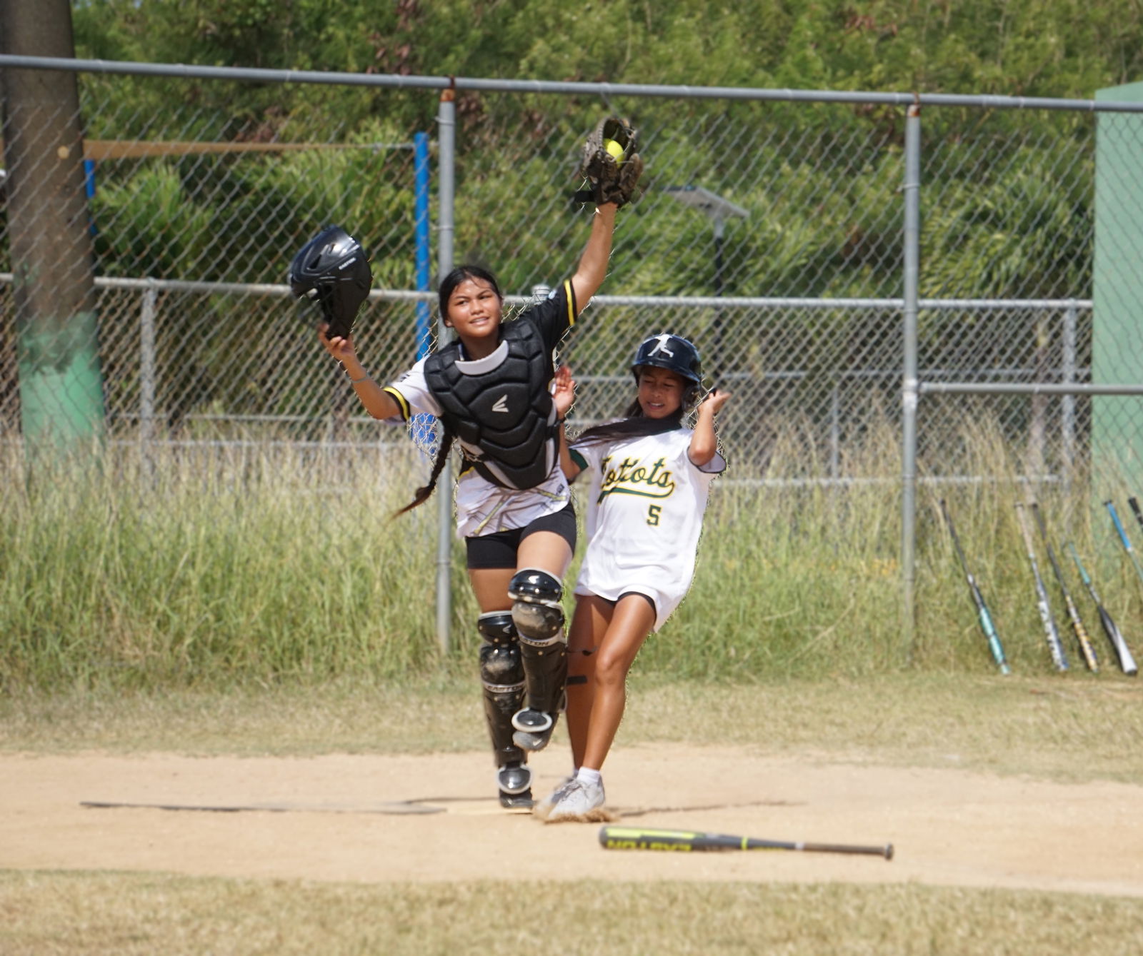 Tanapag Middle School catcher Chelsea secures the ball as a runner scores during a game against Dandan Middle School in the girls middle school division of the PSS-NMISA Interscholastic Fastpitch Softball League SY24-25 at the Dandan softball field on Saturday.