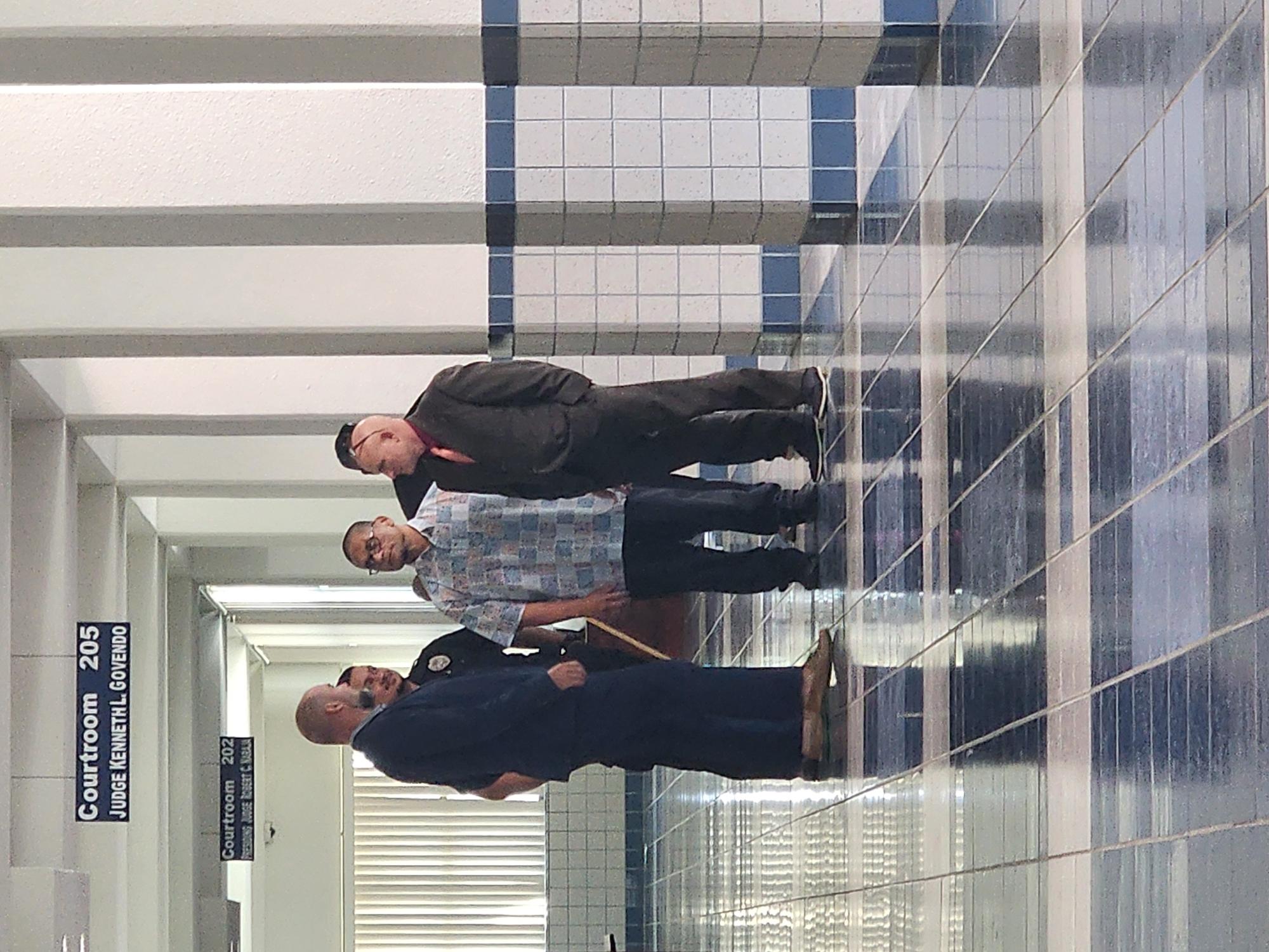 Defendant Calvin Tagabuel, escorted by a Corrections officer, confers with his attorney Joey McDoulett and investigator Jeremy Wolfe at the local courthouse on Wednesday morning.