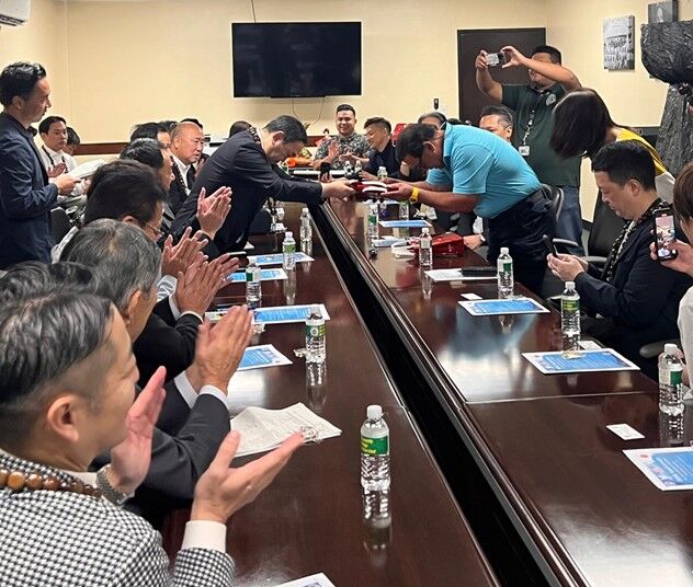 Hiroshima Prefectural Assembly Chairman Takashi Nakamoto, standing left, presents Ramon RB Camacho, mayor of Saipan, with a Kumano brush, a Hiroshima specialty, as a souvenir on Jan. 24, 2025, at the Office of the Mayor of Saipan in The Marianas
