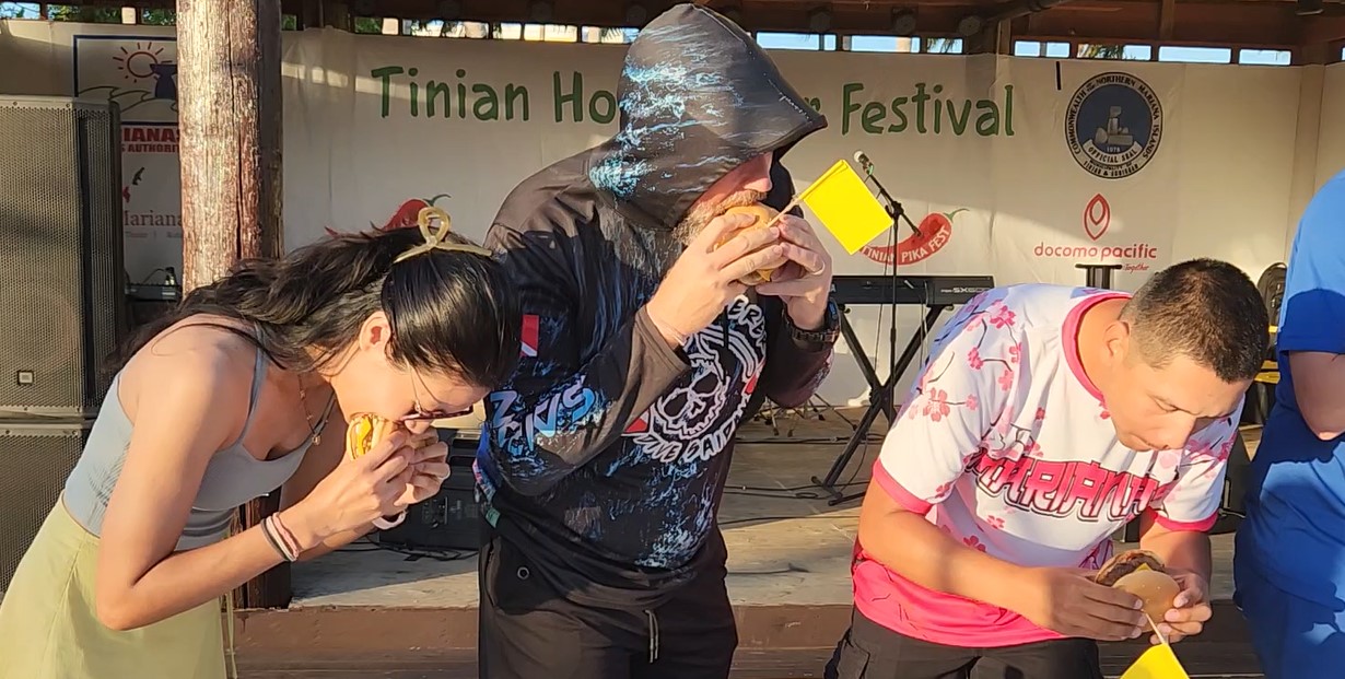 Jay Wolf, center, chomps his way to 1st place in the JC Café Pika Burger Eating Contest during the 21st Annual Tinian Hot Pepper Festival held on Feb. 14-15, 2025, in San Jose, Tinian, in The Marianas.