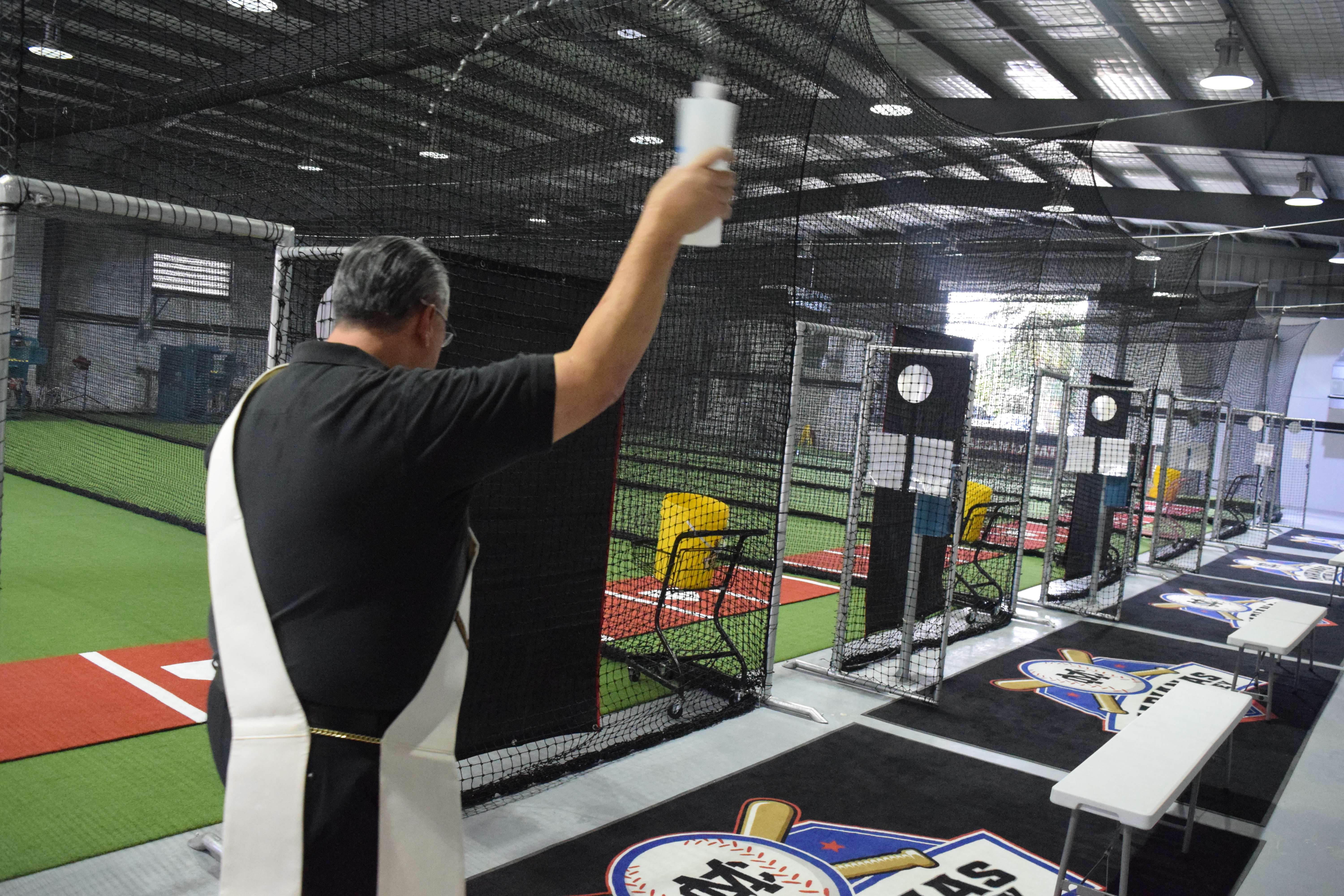 Deacon Stanley Benavente blesses Marianas Batting Alley's facility with holy water.