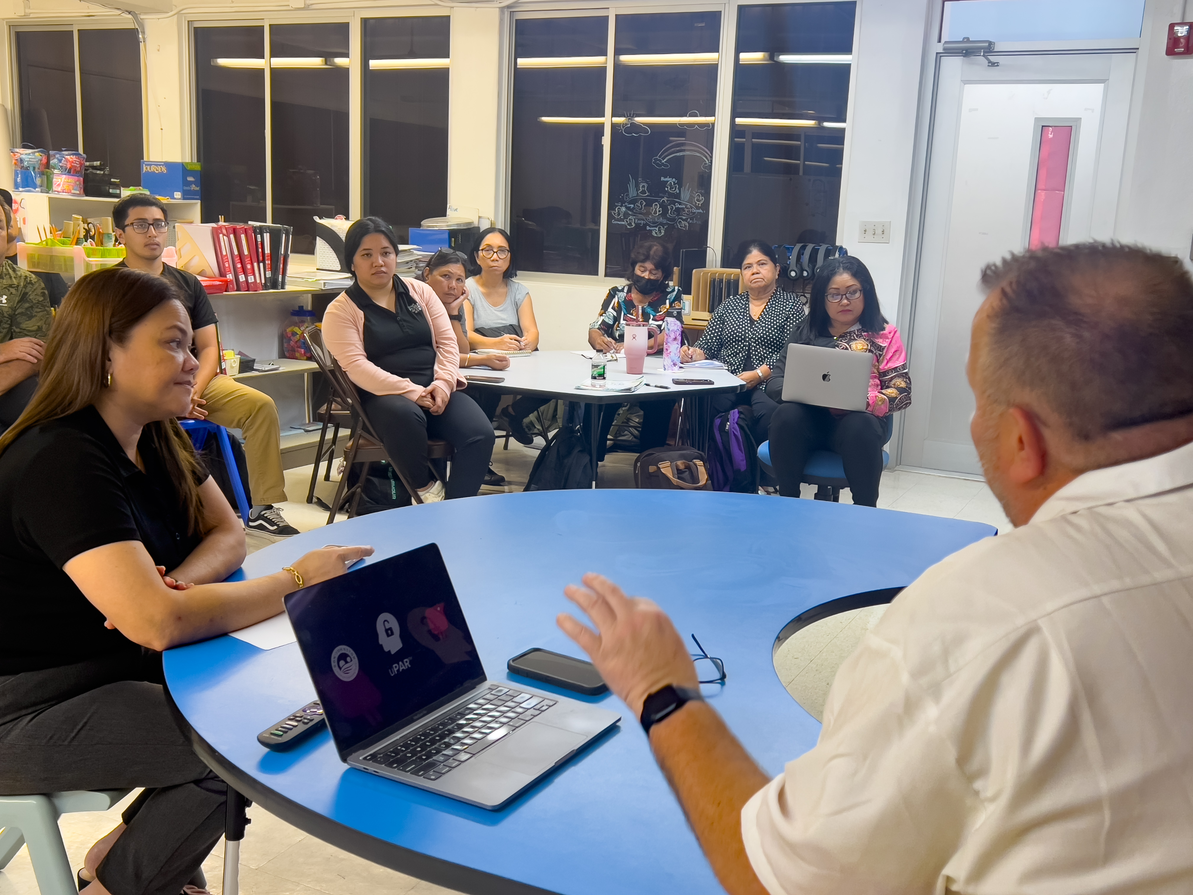 Dave Butler, the national account director for Everway, seated, back to the camera, talks to classroom teachers and school district personnel at Garapan Elementary School.