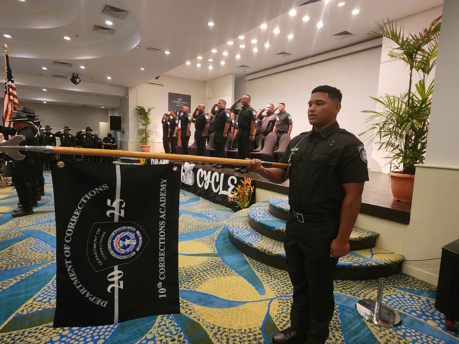 CO1 Lance Sablan holds the 10th Corrections Academy flag, with other members of his batch in the background.