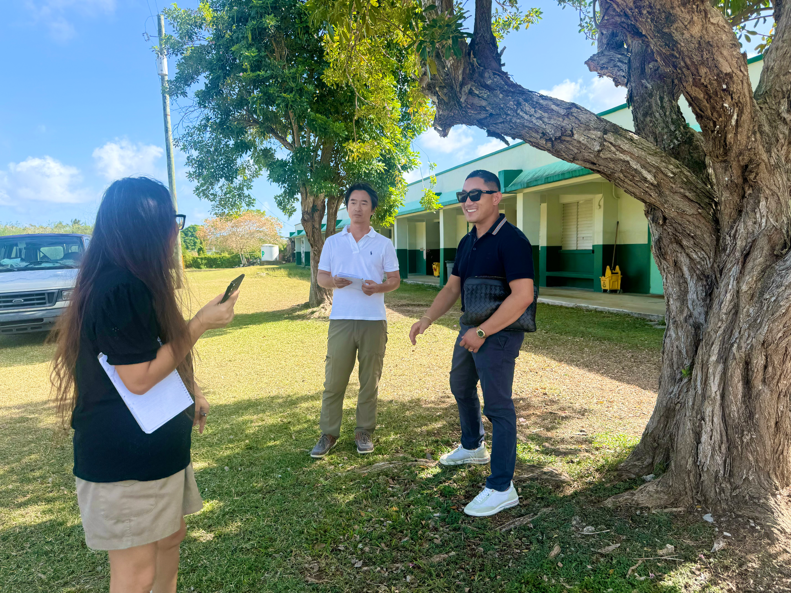 Koblerville Elementary School Principal Naomi Nishimura with CJ Innovation Co. CEO Hwang Hee Jung and Director Kim Jung Hoon in a designated installation area near the tree shades, where new tire pyramids and other tire playground sets will be installed.