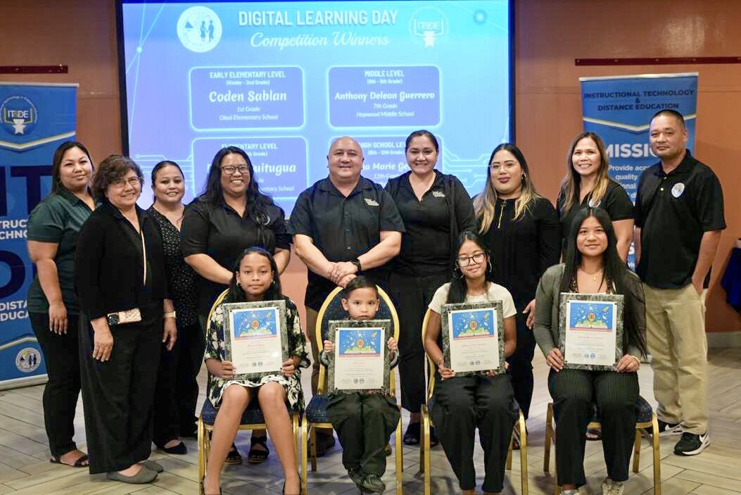 The student winners of the 2025 Digital Learning Day competition: Coden Sablan of Oleai Elementary School, Bernie Quitugua of William S. Reyes Elementary School, Anthony Deleon Guerrero of Hopwood Middle School, who is represented by his sister, and Rihanna Marie Geronimo of Saipan Southern High School. Commissioner of Education Dr. Lawrence F. Camacho, standing center, and ITDE Director Dr. Lorraine Catienza, fourth left, are joined by other Public School System officials in honoring the winners on Monday afternoon.