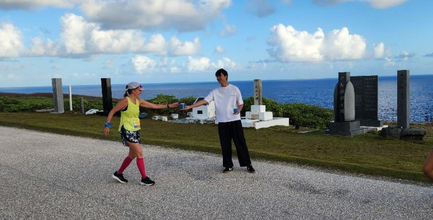 A volunteer offers refreshment to Yvonne Dubois of the U.S. at the full marathon turnaround point of Skechers Saipan Marathon 2025 on March 8, 2025.
