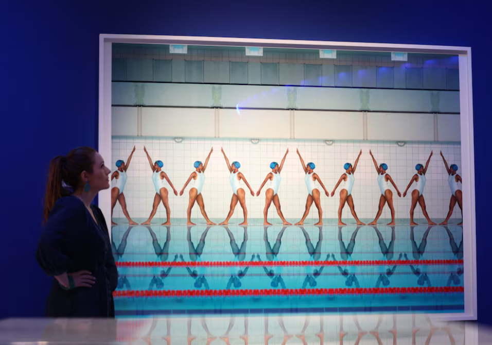 A staff member looks at "Movement" (2020) a photograph by Maria Svarbova on display at the Splash! A Century of Swimming and Style exhibition which will begin at the Design Museum in London, Britain, March 24, 2025.REUTERS