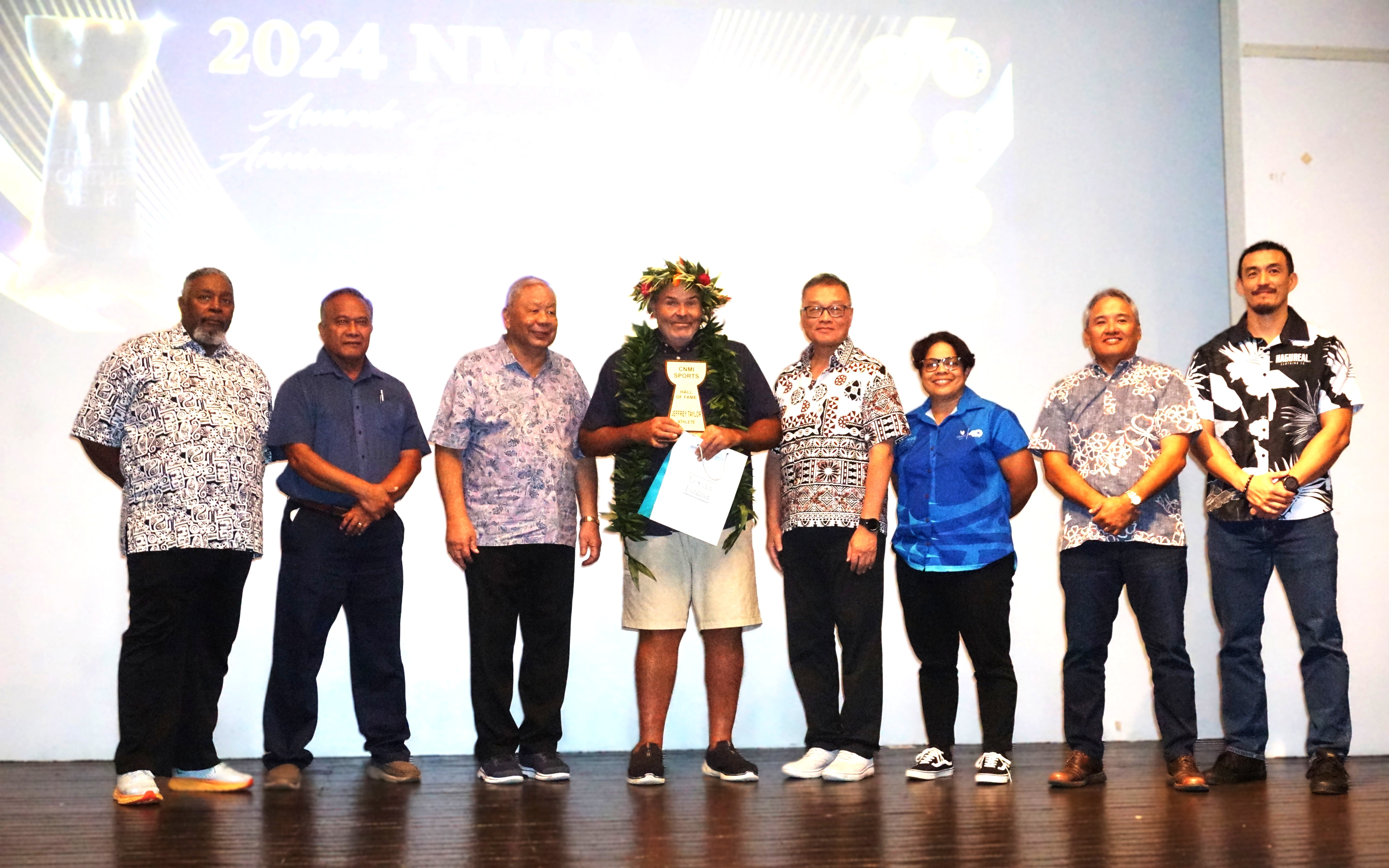 Jeff Taylor, center, smiles as he holds his NMI Sports Hall of Fame trophy while posing for a photo with Lt. Gov. David Apatang and the Northern Marianas Sports Association board members during the 2024 NMSA awards banquet and 40th anniversary celebration at the Taga Hall of Crowne Plaza Resort Saipan on Thursday night.Photo by James F. Sablan Jr.