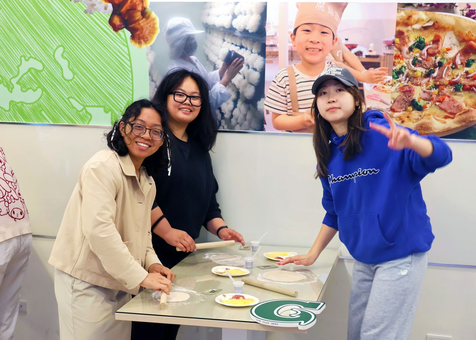 UOG students, from left, Chloe Santos, Grace Dela Cruz, and Daisy Kuo make pizzas using freshly picked mushrooms at a mushroom production facility and agritourism operation in Changhua County, Taiwan.