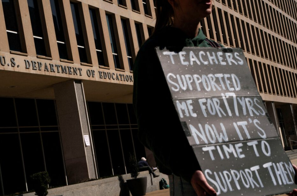 A protester stands near the U.S. Department of Education headquarters after the agency said it would lay off nearly half its staff, in Washington, D.C., March 12, 2025.REUTERS