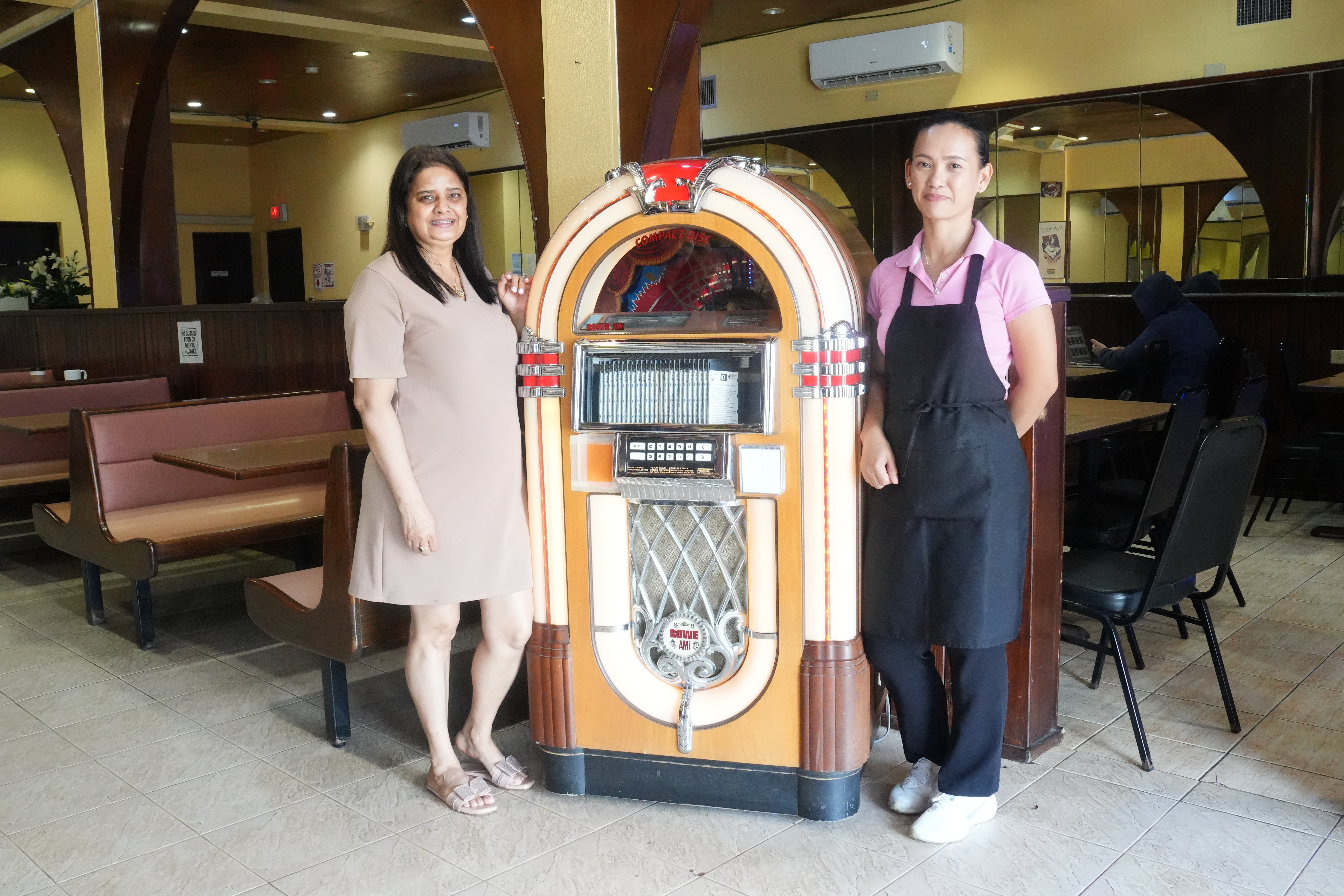 Java Joe’s manager Kathleen Tolentino, right, and cafe owner Manju Pandey, pose by the shop’s vintage jukebox.