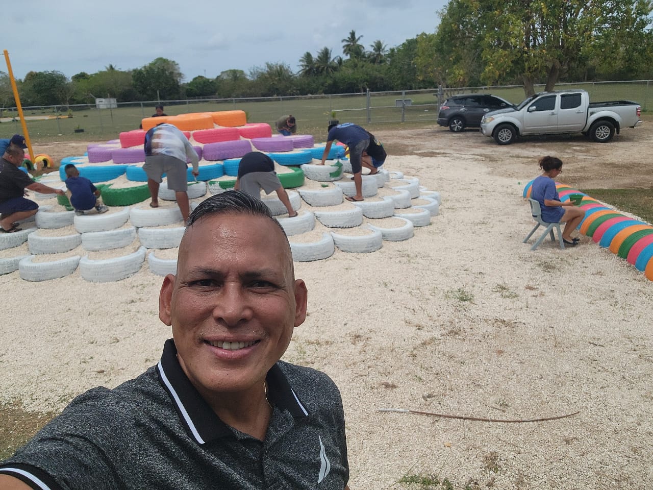 Koblerville Elementary School Vice Principal Jonas Barcinas takes a selfie while volunteers paint a “pyramid” made from old tires.Contributed photo