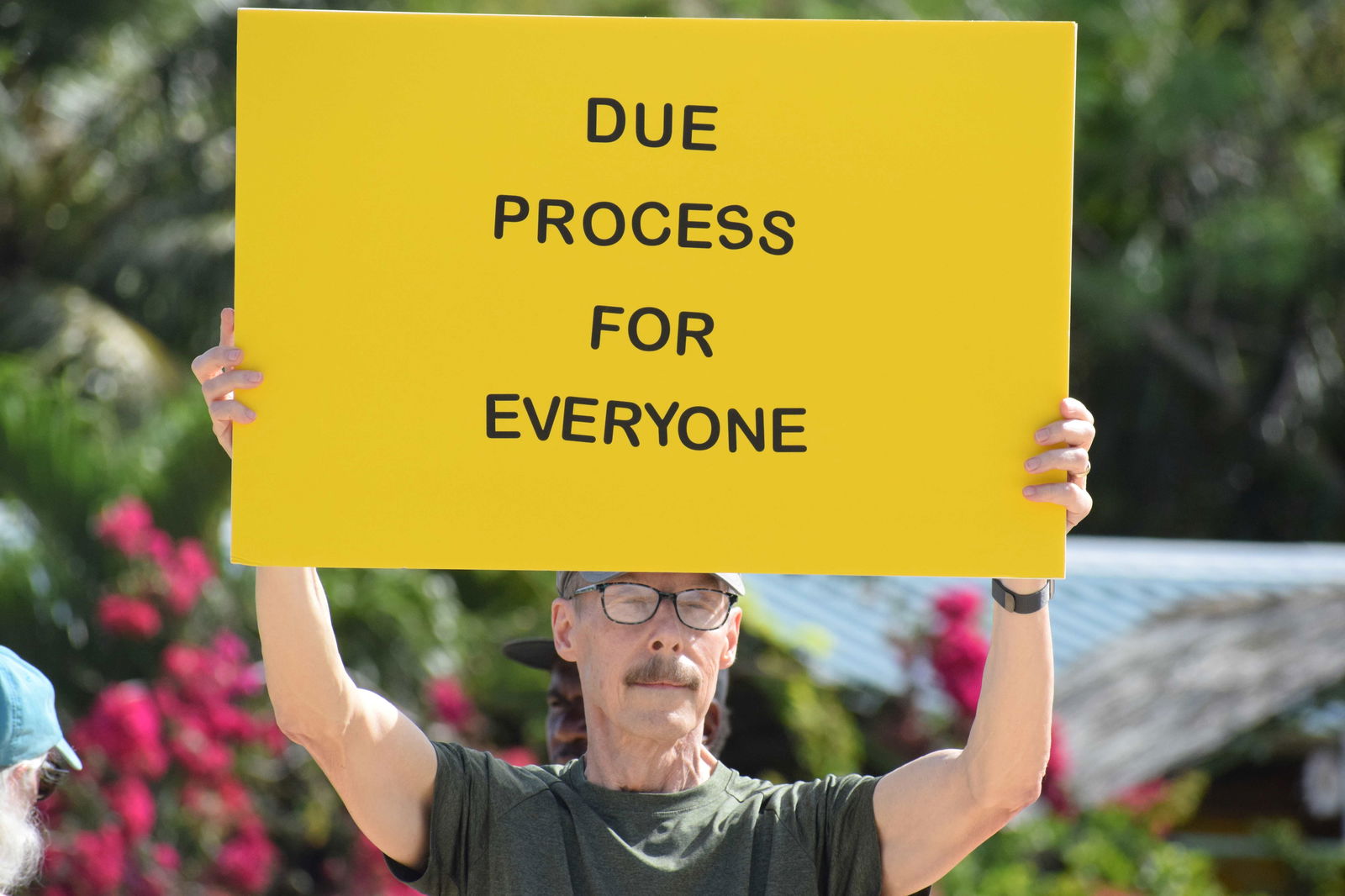 A “hands-off” protester holds a placard that says, “Due Process for Everyone.”