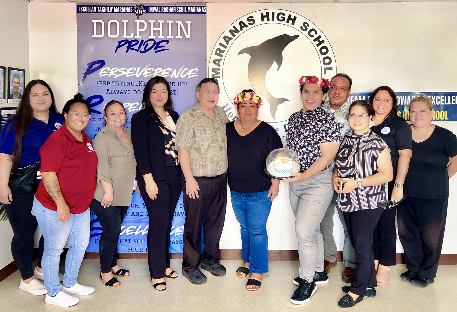 One of the two vice principals of Marianas High School, A. Romolo Orsini, smiles after he was presented with a mwar and a miniature cake by Board of Education Acting Chairman Anthony Dela Cruz Barcinas, fourth right, BOE member Andrew L. Orsini, fifth left, and Acting Commissioner of Education Jacqueline P. Che, fourth left, on Friday. Also in photo are MHS Principal Melanie Rdiall, PSS Human Resources Officer Lucretia Deleon Guerrero, Finance Director Arlene Lizama, Special Education State Director Donna M. Flores, Career and Technical Education Director Dr. Jessica Taylor, and BOE staff members Jocelyn Saures and Mary-Jo Camacho.