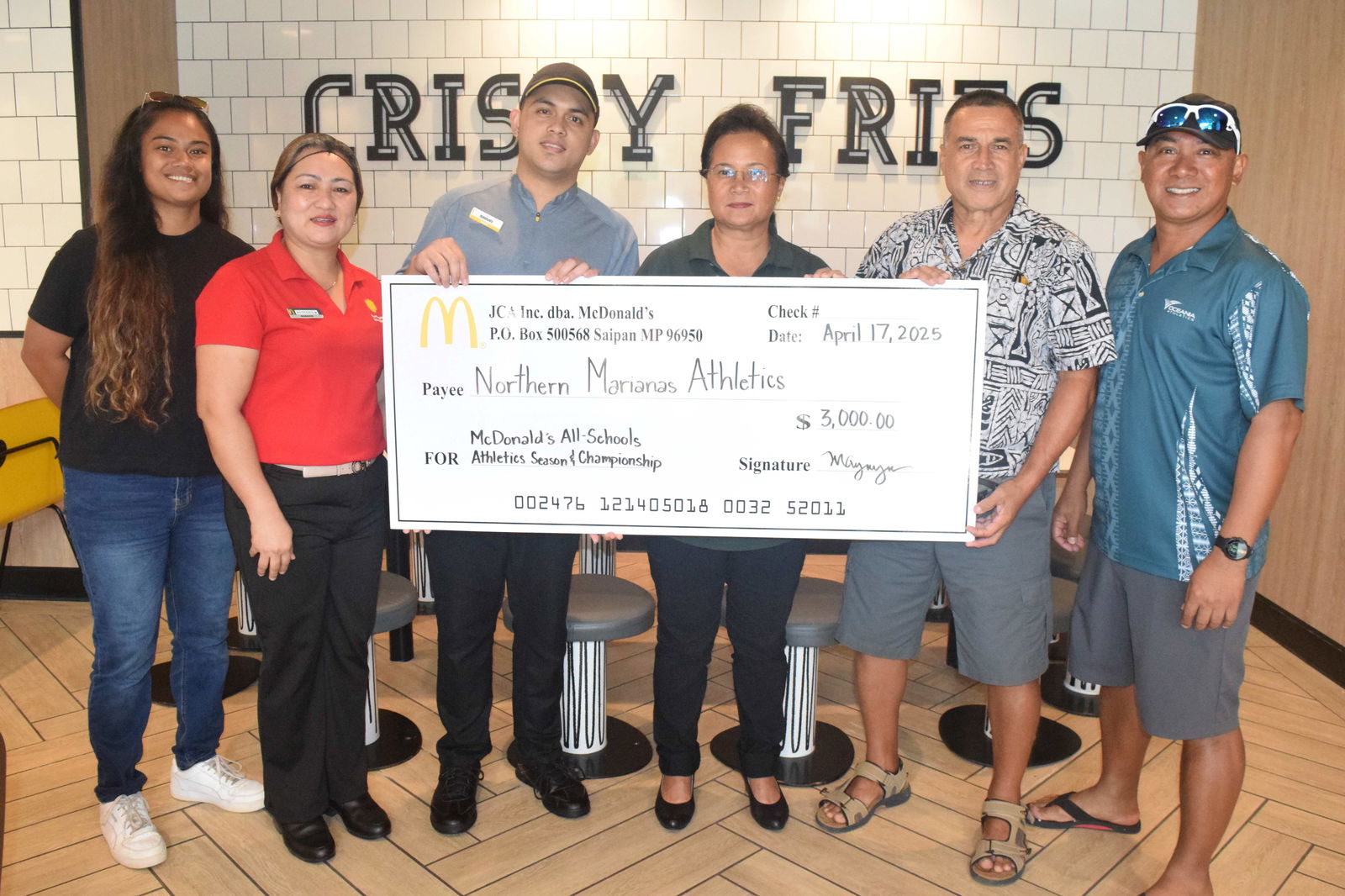 McDonald's Restaurant of Guam and Saipan owner/operator Marcia Ayuyu and Rep. Elias Rangamar hold a ceremonial check for $3,000 for the McDonald’s All-Schools Championship on Thursday. Also in photo are NMA Vice President Lia Rangamar, left, Oceania President Robin Sapong, right, McDonald's Middle Road general manager Ruthzel Perez, second left, and service crewmember Marvin, third left.Photo by Emmanuel T. Erediano