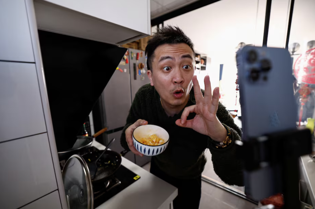 Yu Bo, a content creator on Chinese social media platform Xiaohongshu, also known as RedNote, speaks to his camera as he records a cooking session during an interview with Reuters at his apartment in Beijing, China Feb. 26, 2025.REUTERS