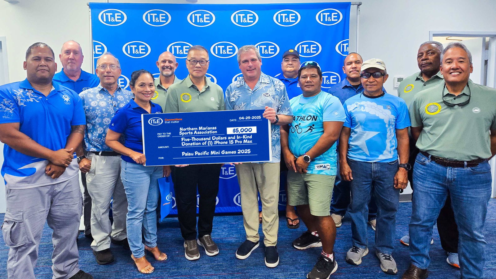IT&E Chief Executive Officer David Gibson and Executive Director Velma Ann Palacios hold the ceremonial $5,000 check as they join Northern Marianas Sports Association President Jerry Tan, center, and other members of Team Marianas on Tuesday at the IT&E main office in Susupe.Contributed photo