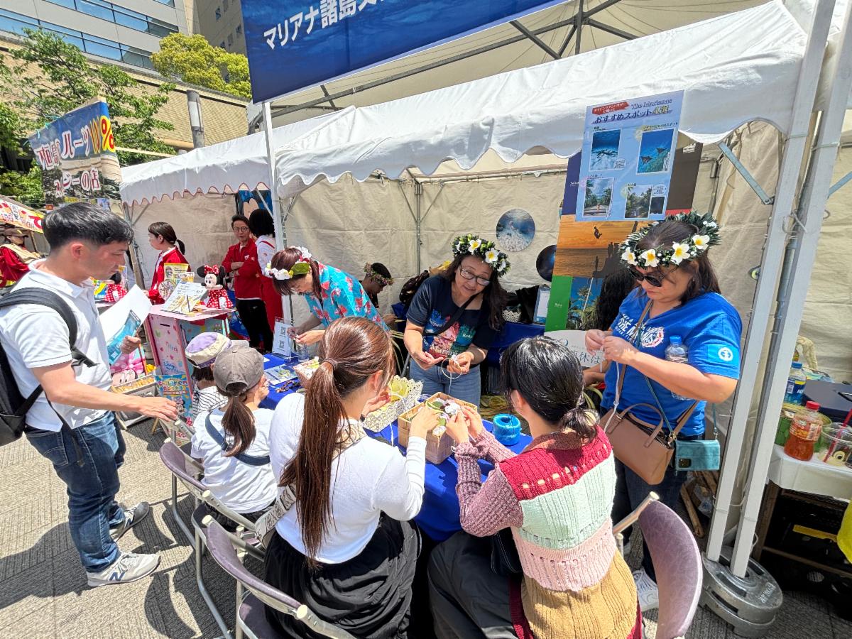 Festivalgoers at Hiroshima Flower Festival 2025 on May 3-5, 2025 in Hiroshima, Japan, learn “mwar”-making at The Marianas booth. Marianas Visitors Authority Deputy Managing Director Judy C. Torres, right, led a Marianas delegation in marketing Tinian, Saipan, and Rota to 1.7 million attendees of the event, the largest annual festival in Hiroshima.