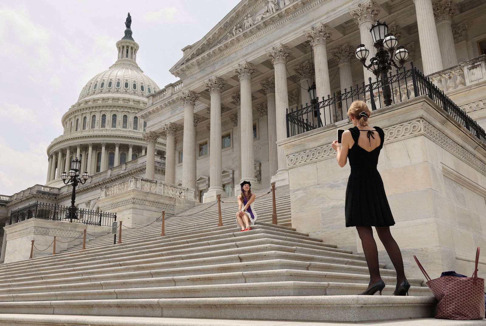 A graduate has her photo taken at the U.S. Capitol on the day President Donald Trump's sweeping tax bill failed to clear a key procedural hurdle as hardline Republicans demanding deeper spending cuts blocked the measure in a rare political setback for the Republican president in Congress, in Washington, D.C., May 16, 2025.REUTERS