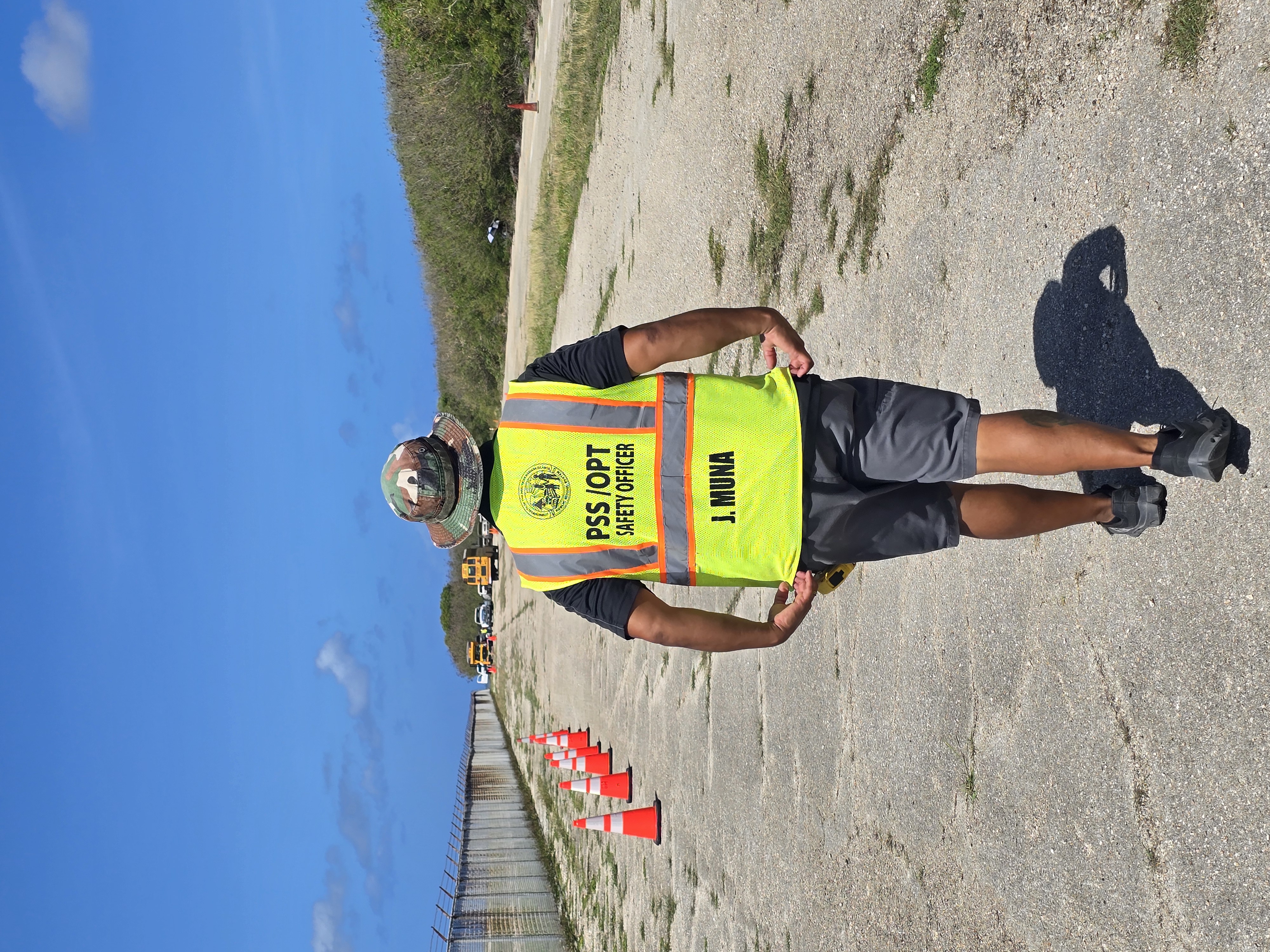 OPT Safety Officer and Training Coordinator Joseph Muna signals to the driver of a school bus from a distance.