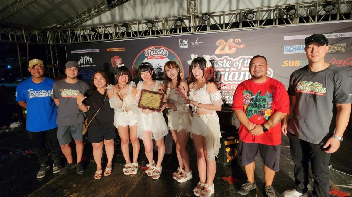 J-pop’s SkySyllabus is named Marianas Goodwill Ambassador during their performance at the 26th Annual Taste of The Marianas International Food Festival on May 24, 2025, at American Memorial Park, Saipan. Presenting the appointment plaque is Marianas Visitors Authority Deputy Managing Director Judy C. Torres, third left, and other MVA management and staff.