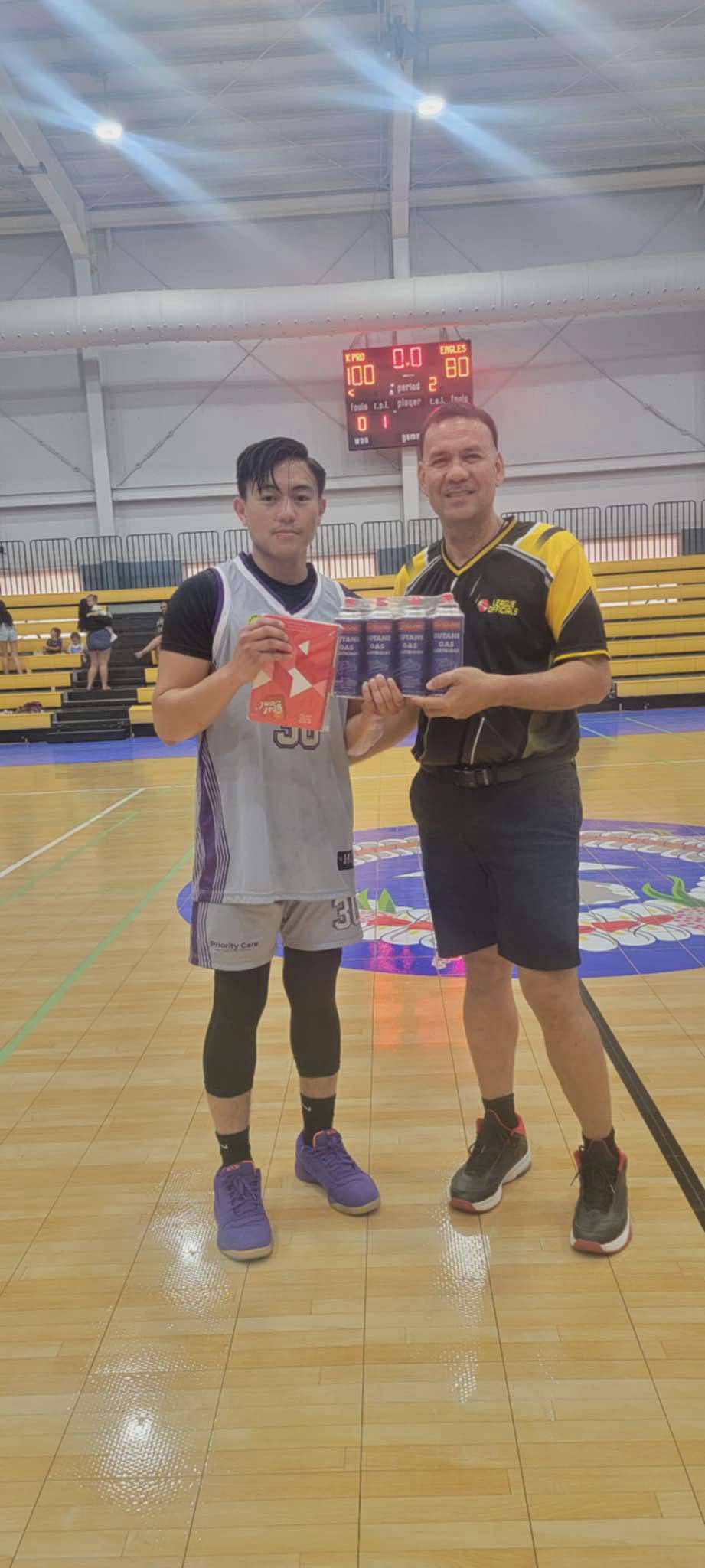 Priority Care’s Steve King, left, poses with League Commissioner Bernie Ebuen as he receives a case of butane gas, sponsored by Best Deal, as the Best Player of the Game at the Ada gym on Sunday.Contributed photo