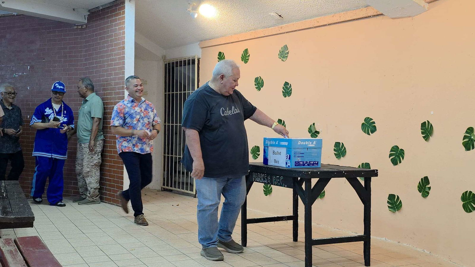 Local businessman Juan “Santiago” Tenorio casts his ballot as former Sen. Vinnie Sablan waits his turn with a smile