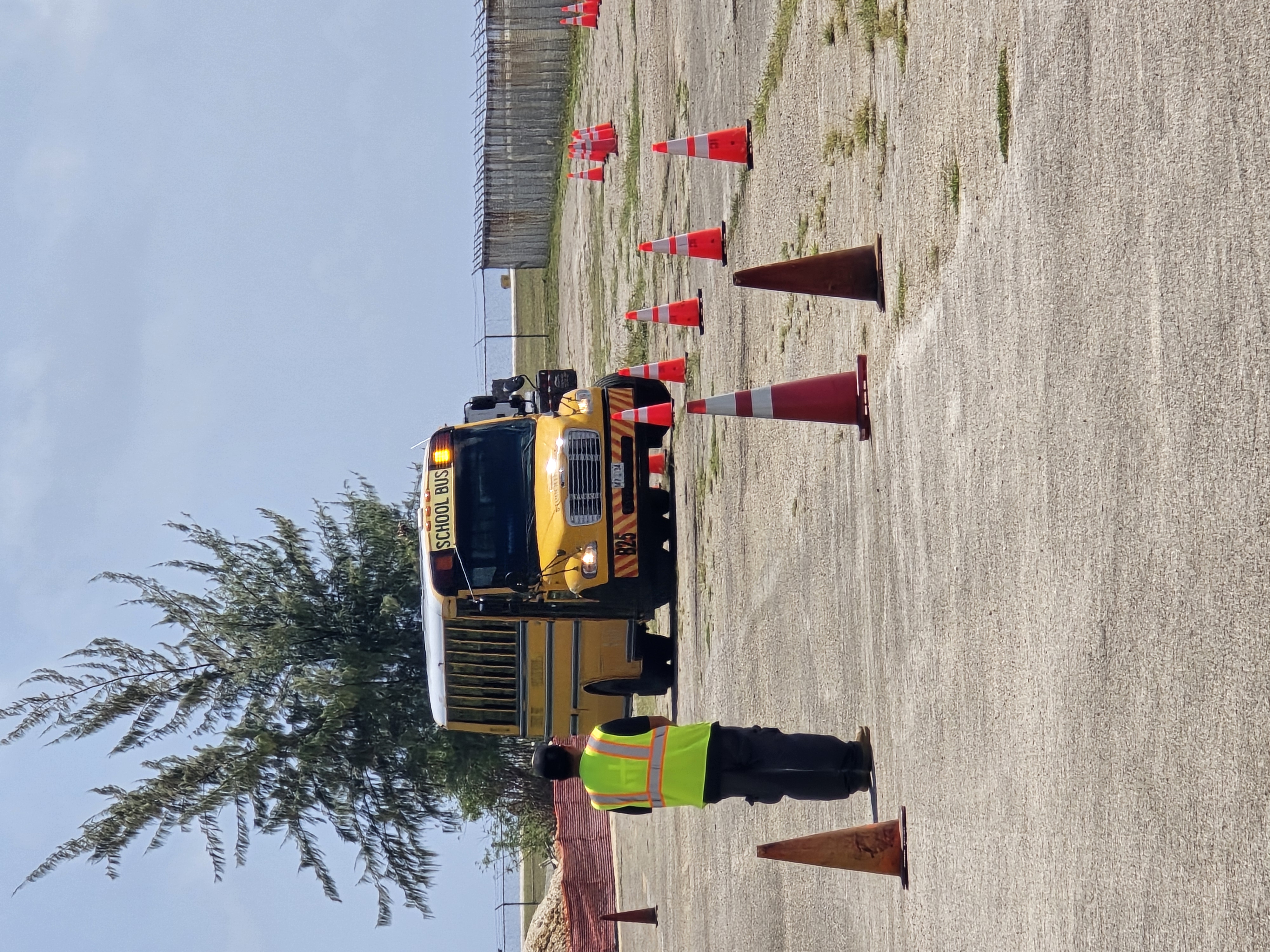 An OPT staff member watches a driver maneuver a school bus.