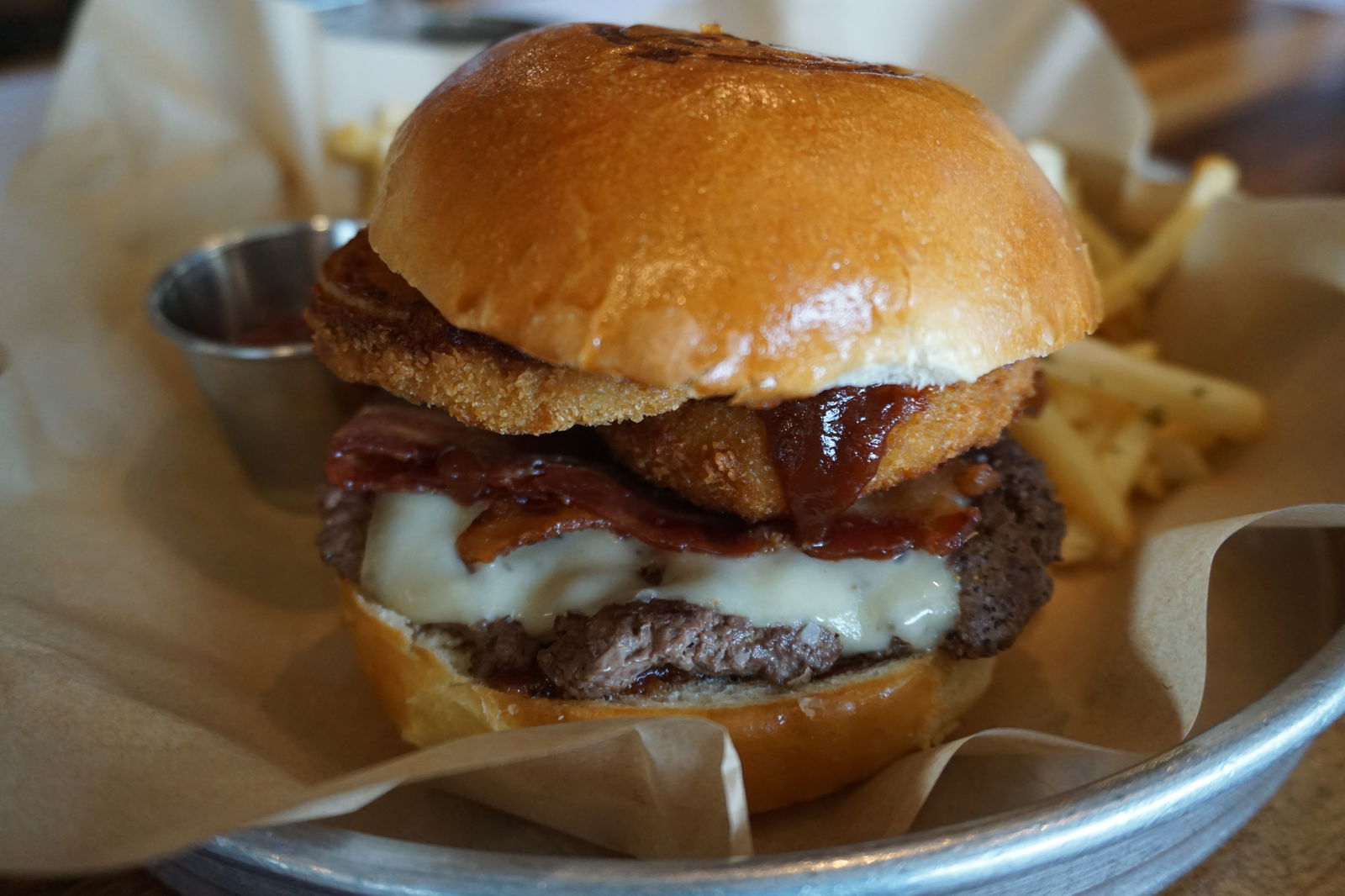 Your BBQ Bacon Burger order is coming to your table hot and fresh with barbecue sauce, Swiss cheese, onion rings, a steak burger patty, and crispy bacon. 