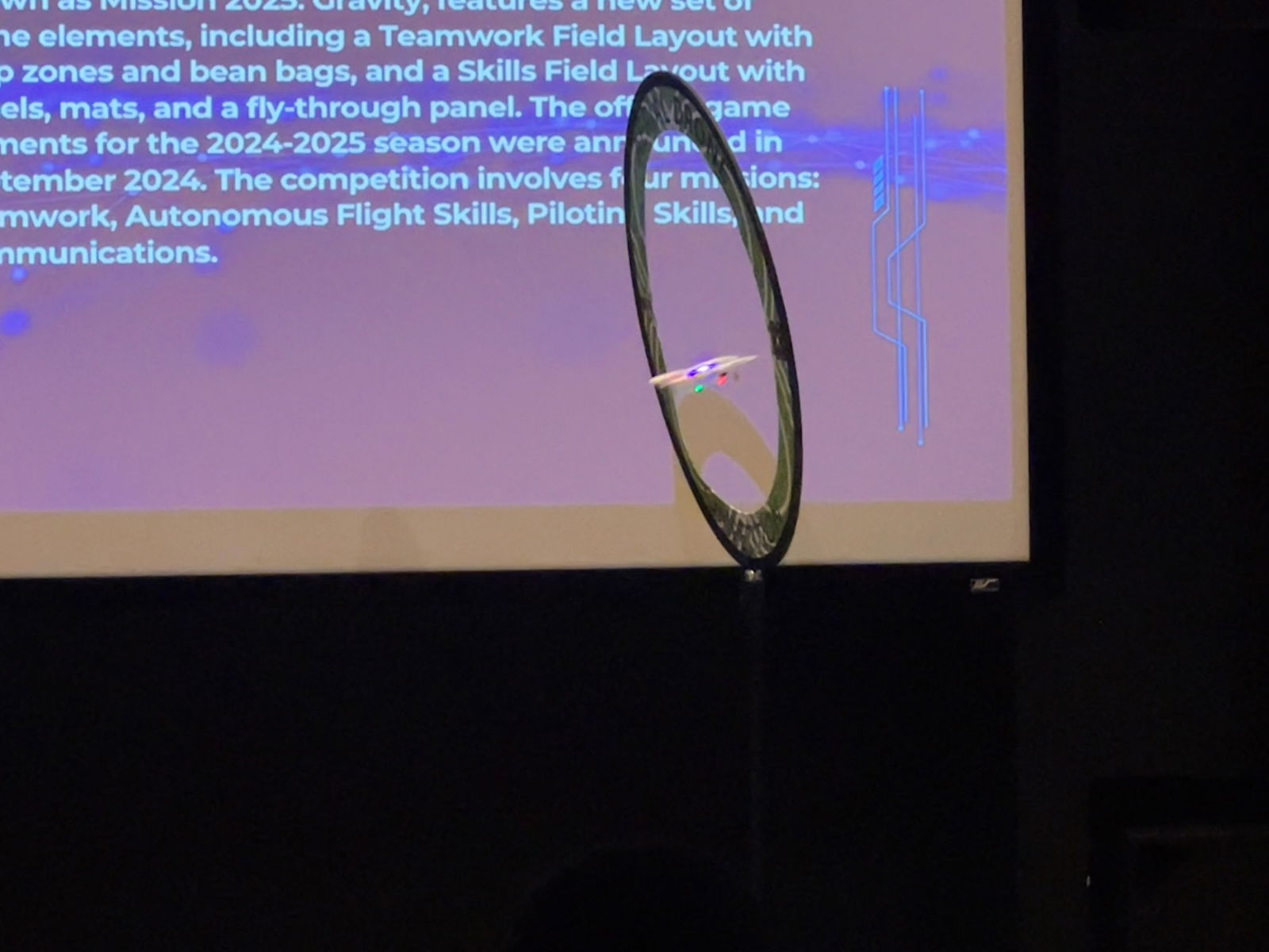 A drone programmed by the Marianas High School team soars through a ring during a demonstration.