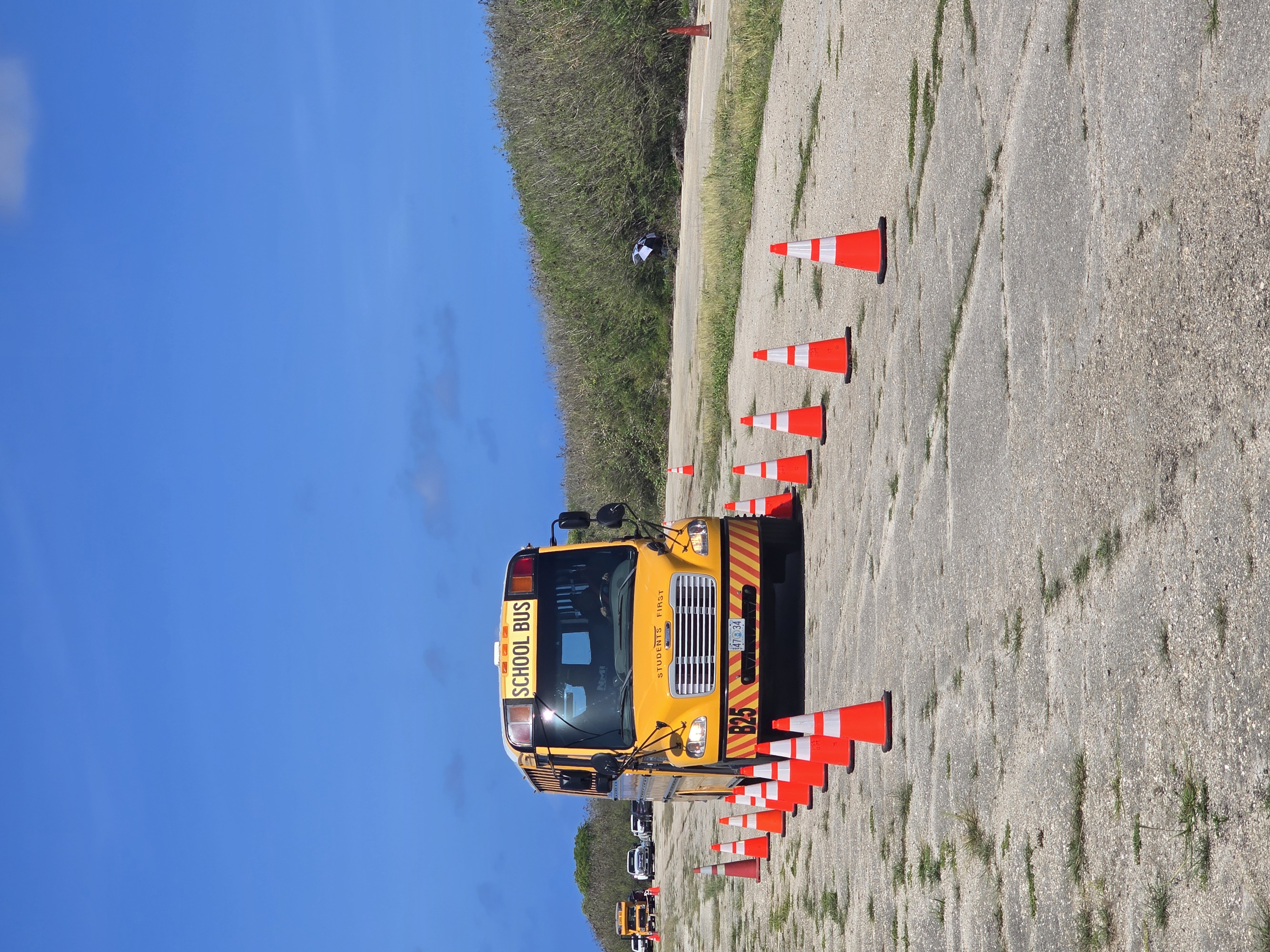 A school bus driver carefully navigates a tight, coned-off lane.