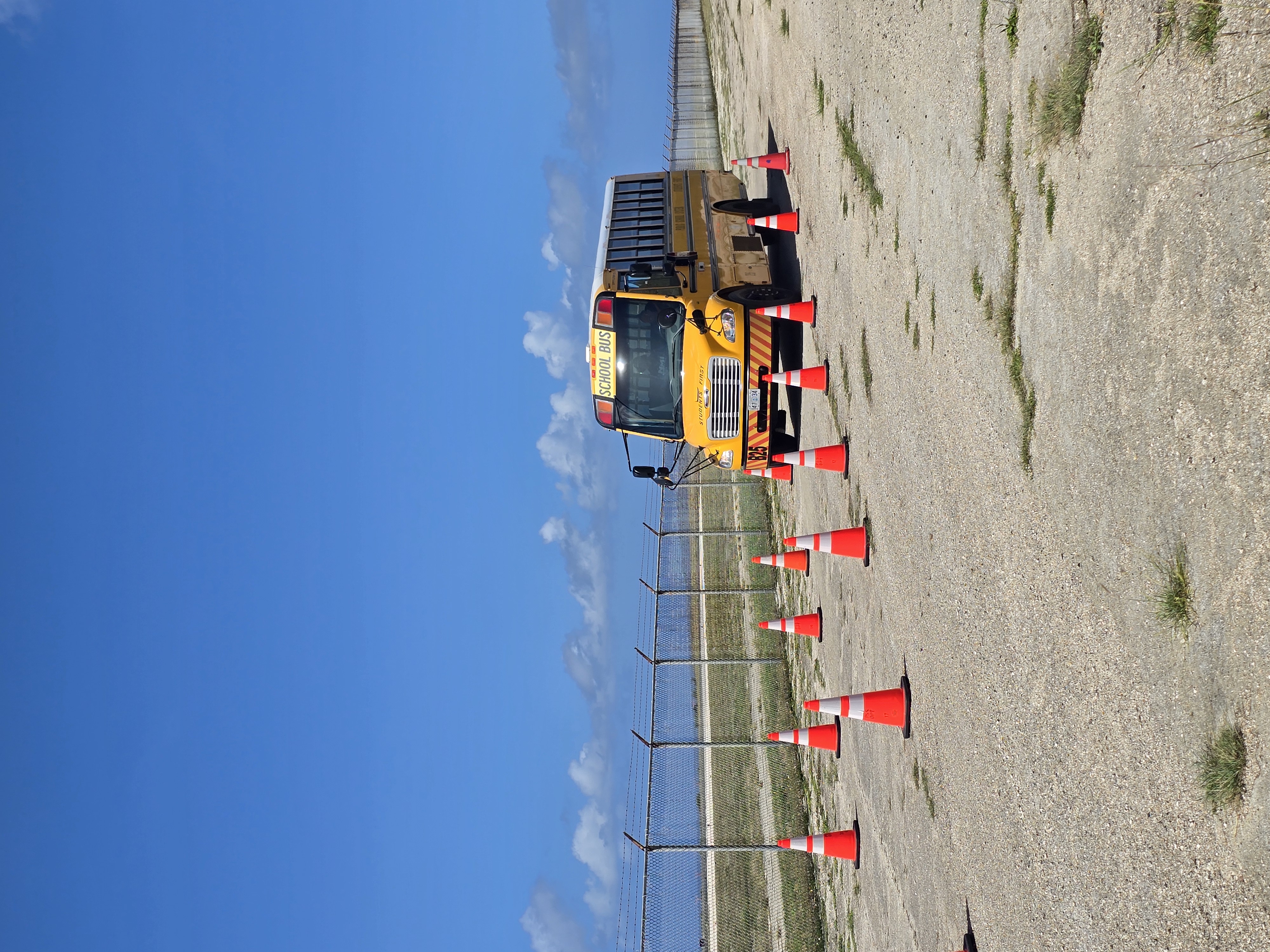 A school bus operator drives through a narrow, coned-off lane.