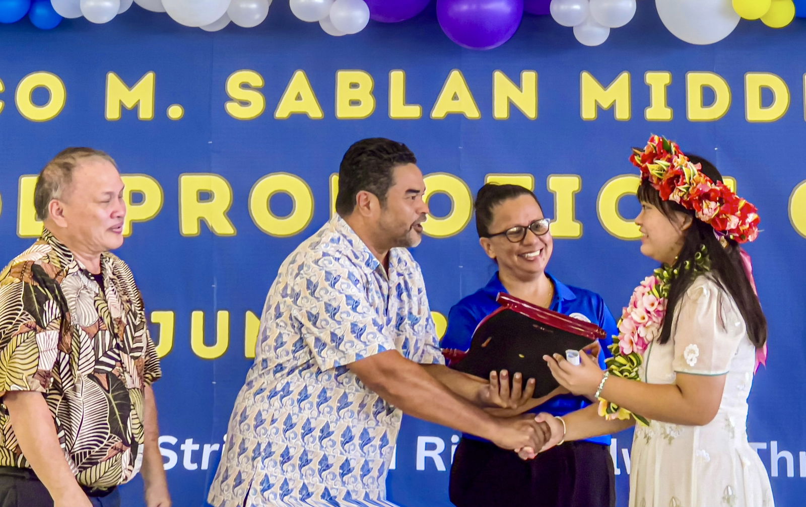 Board of Education Chairman of Aschumar Kodep Ogumuro-Uludong congratulates Francisco M. Sablan Middle School valedictorian Yuanyuan “Wren” Xu as BOE members Andrew L. Orsini and Maisie B. Tenorio look on