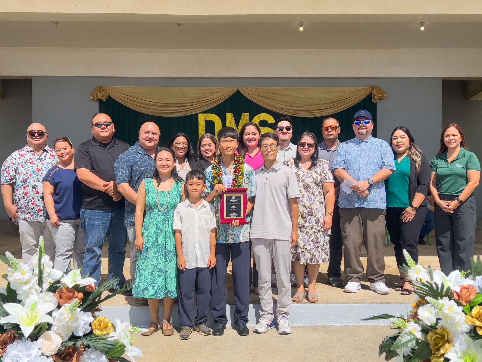 Class valedictorian and recipient of the Board of Education Academic Excellence Award Clyde Manangan poses for a photo with his family. Joining them on stage are BOE Chairman Aschumar Kodep Ogumoro-Uludong, BOE Vice Chairman Anthony DLC Barcinas, BOE Member Andrew L. Orsini, Teacher Representative Dr. Dora Miura, Sen. Ronnie Calvo, Saipan Major RB Camacho, Dandan Middle School Vice Principal James Sablan and Vice Principal Reo Arriola.
