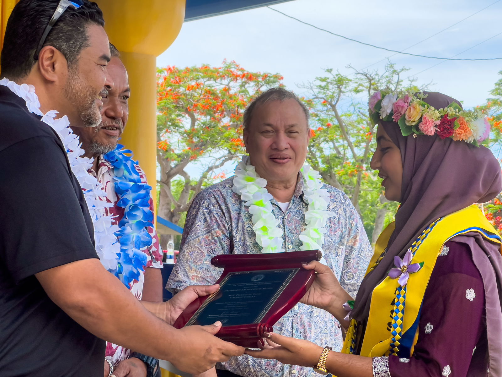 Class valedictorian Mst. Tharatun B. Tazri receives the Board of Education Academic Excellence Award from BOE Chairman Aschumar Kodep Ogumuro-Uludong while Vice Chairman Anthony Dela Cruz Barcinas, and BOE member Andrew L. Orsini look on.