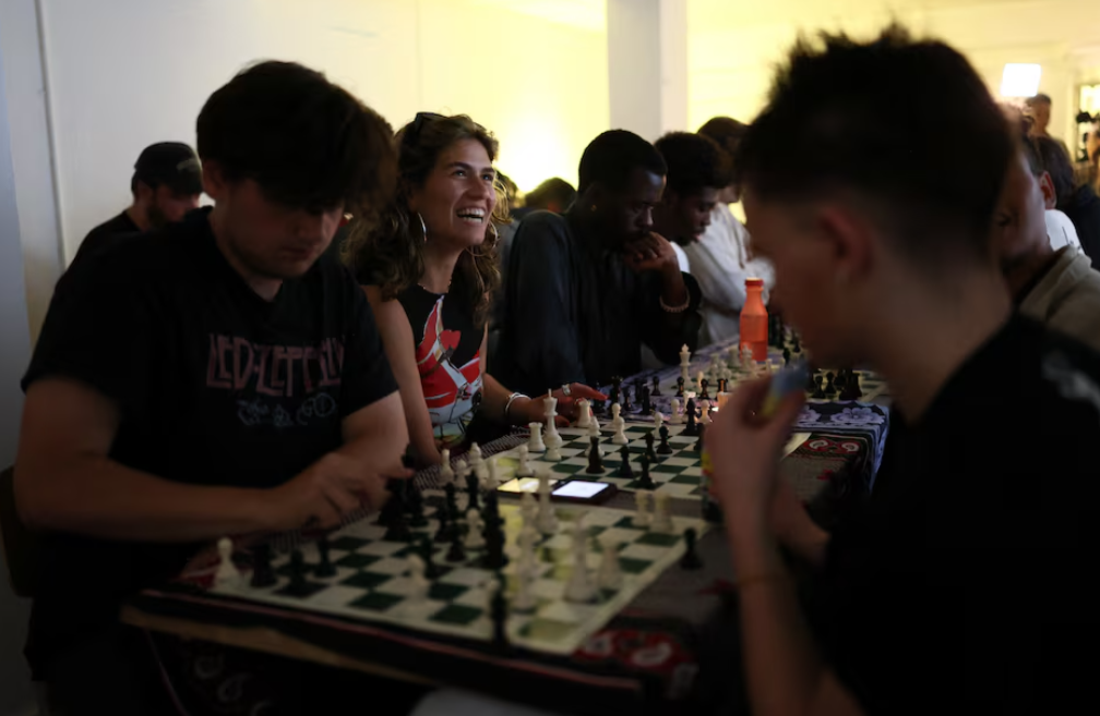 Emily Raad, 28, from east London, reacts while playing chess at Knight Club, a diverse chess club growing to almost a thousand members within a year, based at Fleet Studios, in London, Britain, June 3, 2025.REUTERS
