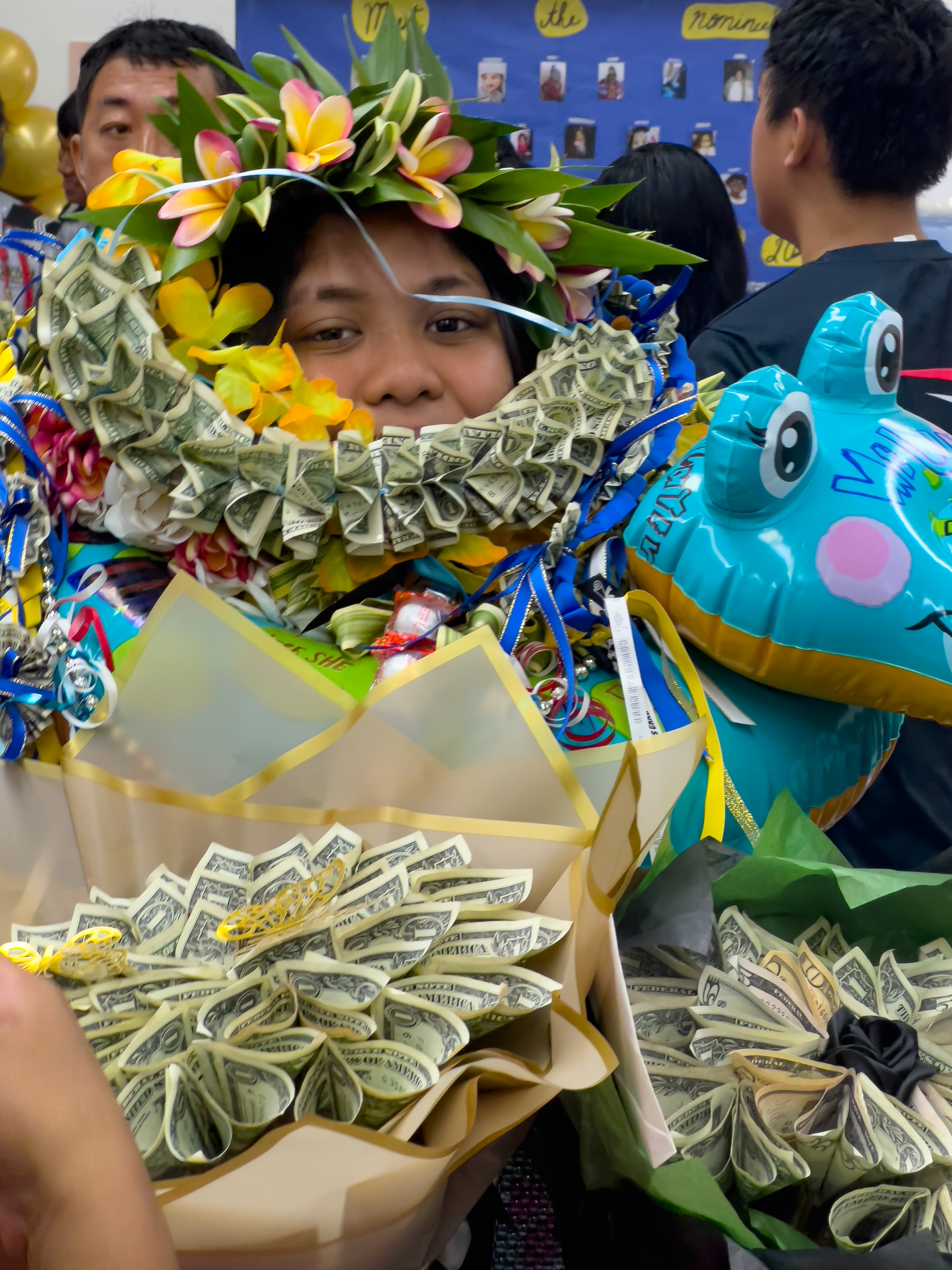 A promoted student wears a money lei and holds money bouquets she received from her family.