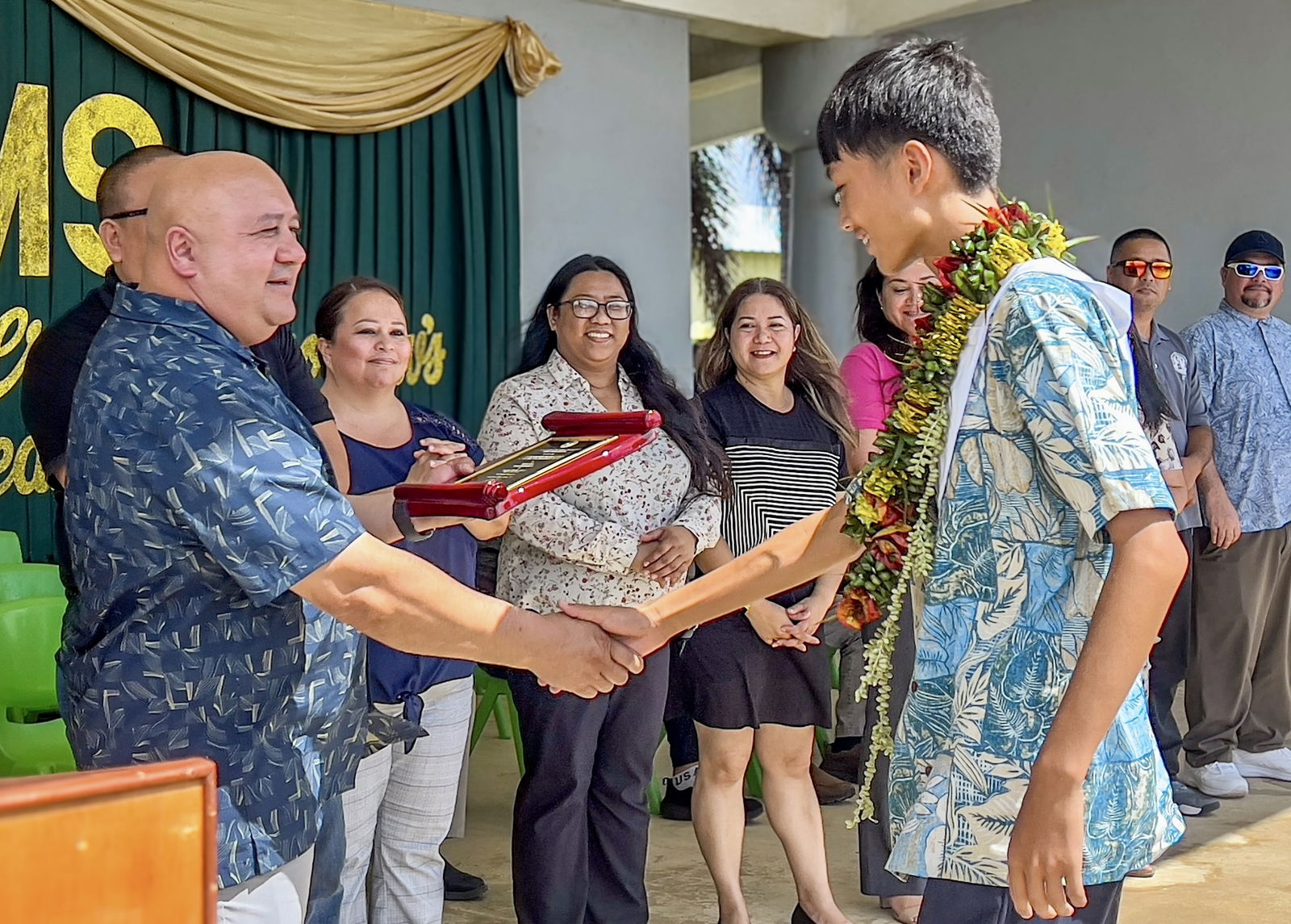 Commissioner of Education Dr. Lawrence F. Camacho congratulates class salutatorian Yuxi Lu as Public School System officials look on.