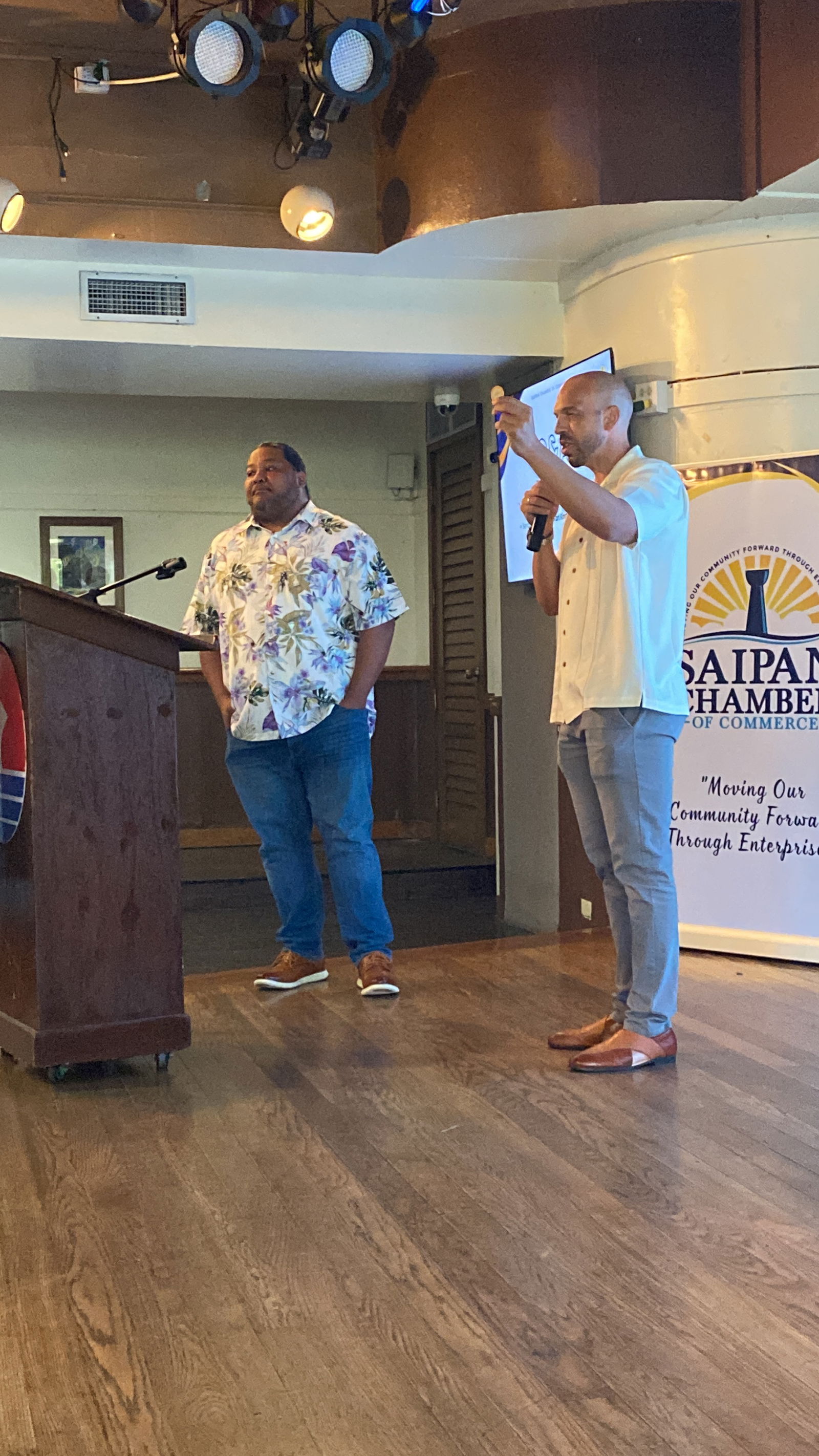 Vin Armani, right, holds a token from the Taste of the Marianas food festival as he explains how the MUSD works for e-gambling operations on Tinian.