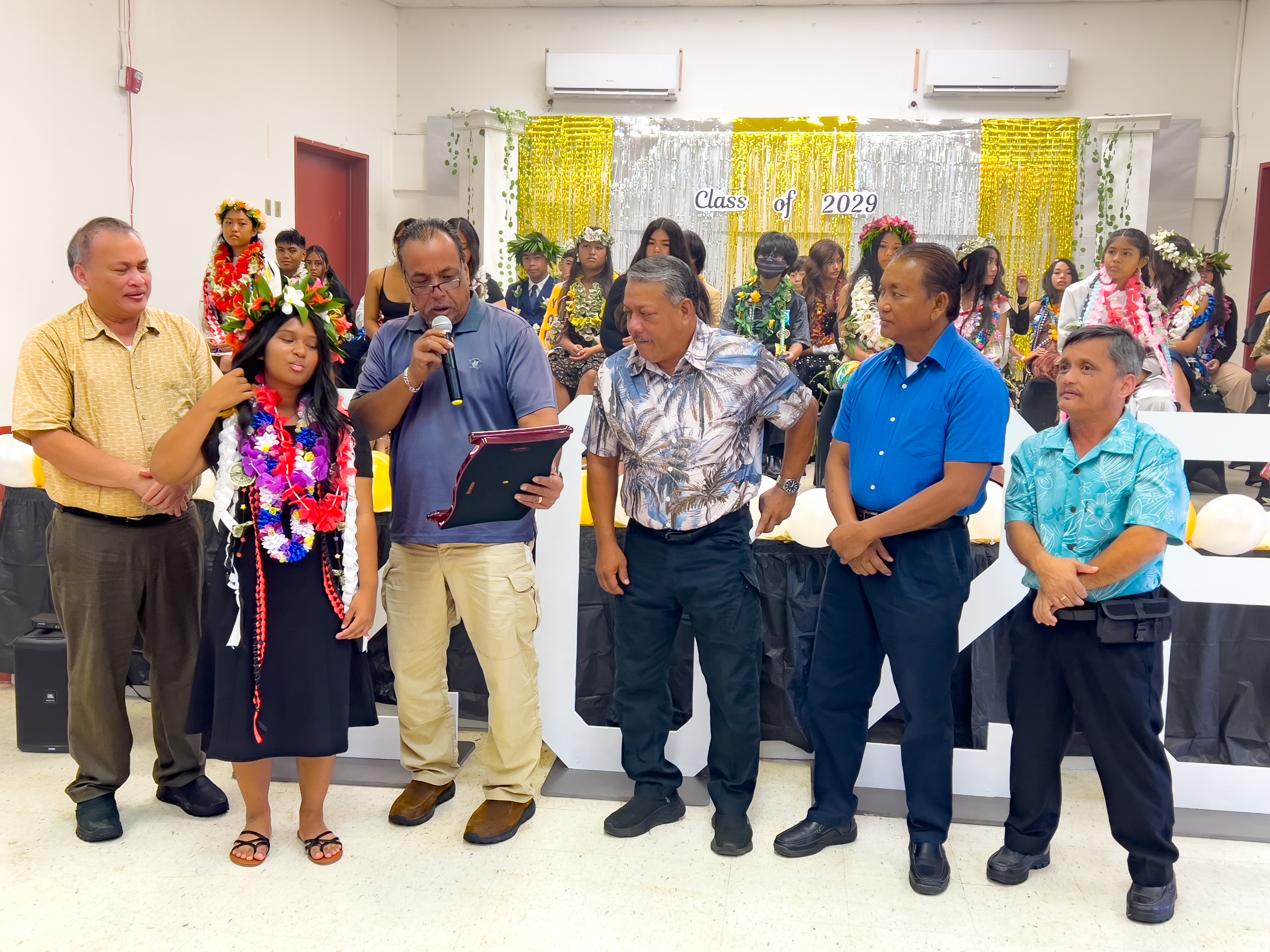 BOE Vice Chairman Anthony DLC Barcinas presents the Board of Education Academic Excellence Award to class valedictorian Amina Fajamida Vera Hossain while BOE Member Andrew L. Orsini, Tinian and Aguiguan Mayor Edwin P. Aldan, Tinian Sen. Francisco Cruz and Municipal Councilman Estevan P. Cabrera look on.