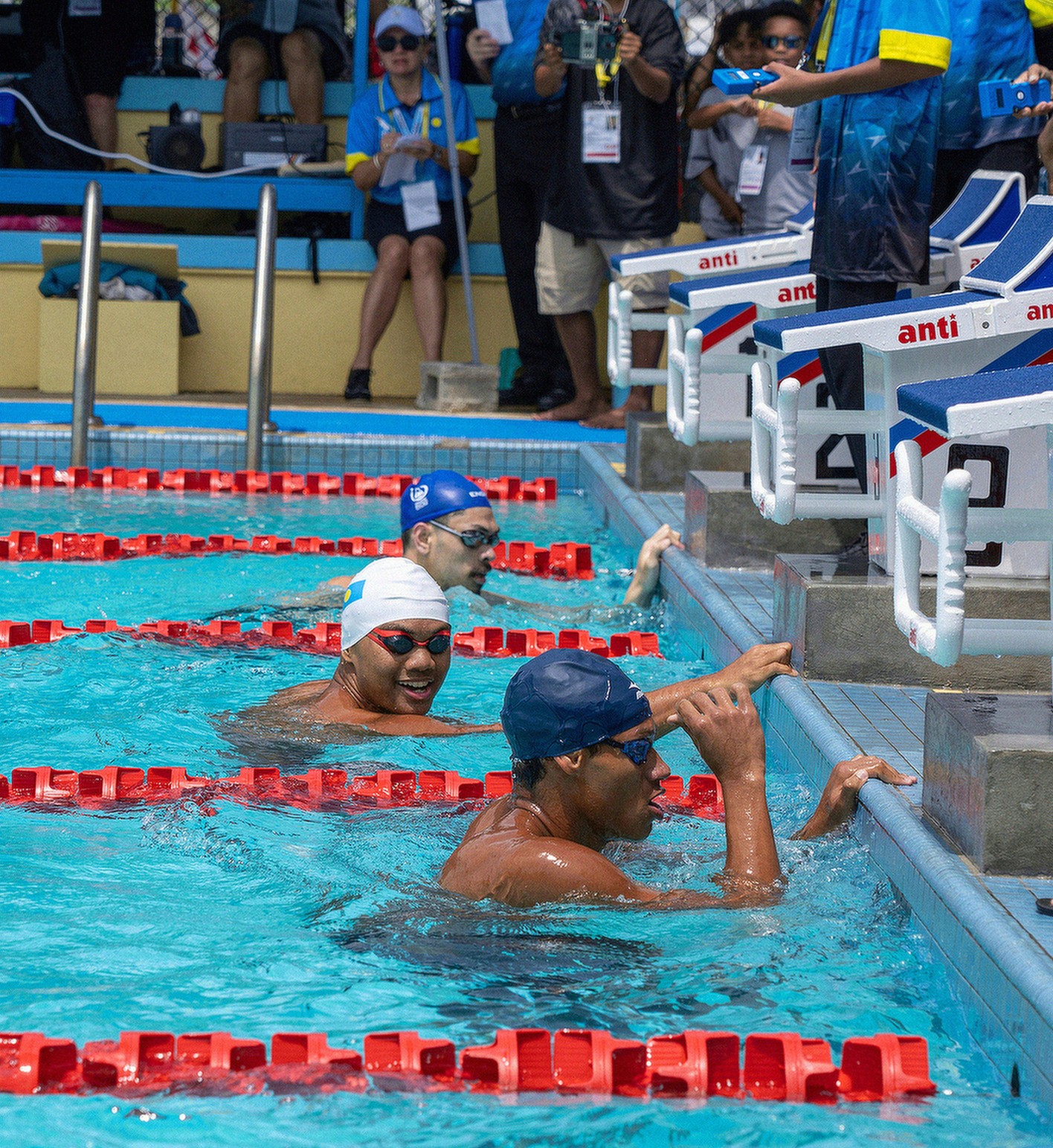 NMI’s Isaiah Aleksenko, right, takes a breather after a first-place finish in the qualifying heat for the 200m butterfly race Thursday morning on Day 4 of the swimming competition in the 2025 Pacific Mini Games in Palau.Photo by Ryota Nishida via NMSA