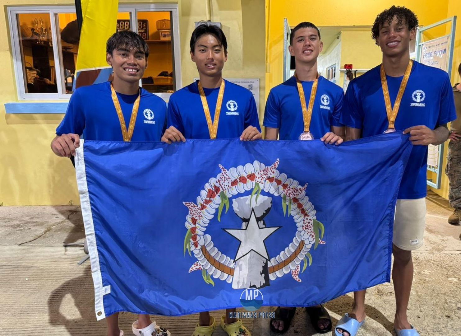 From left, Kean Pajarillaga, Justin Ma, Michael Miller, and Isaiah Aleksenko proudly pose with the CNMI flag after their podium finish in the 4x100m freestyle event.Marianas Press via NMSA