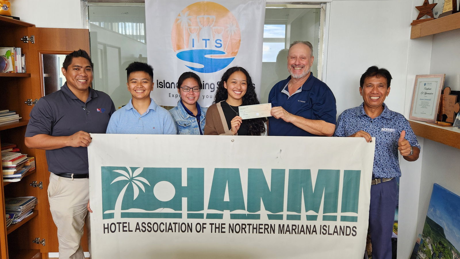 Island Training Solutions owner Jim Arenovski presents a check for $1,200 on July 3, 2025, at the ITS office in Susupe, Saipan, to the organizing committee of the 23rd Annual HANMI Charity Classic Golf Tournament.  The tournament will be held on July 26, 2025, at LaoLao Bay Golf Resort.  From left, tournament committee member Archie Ajoste, ITS IT/program facilitator Marielle Lim, accountant Alyanna Ignacio, program coordinator ReavenJei Cruz, Arenovski, and committee chairman William Retardo.HANMI photo