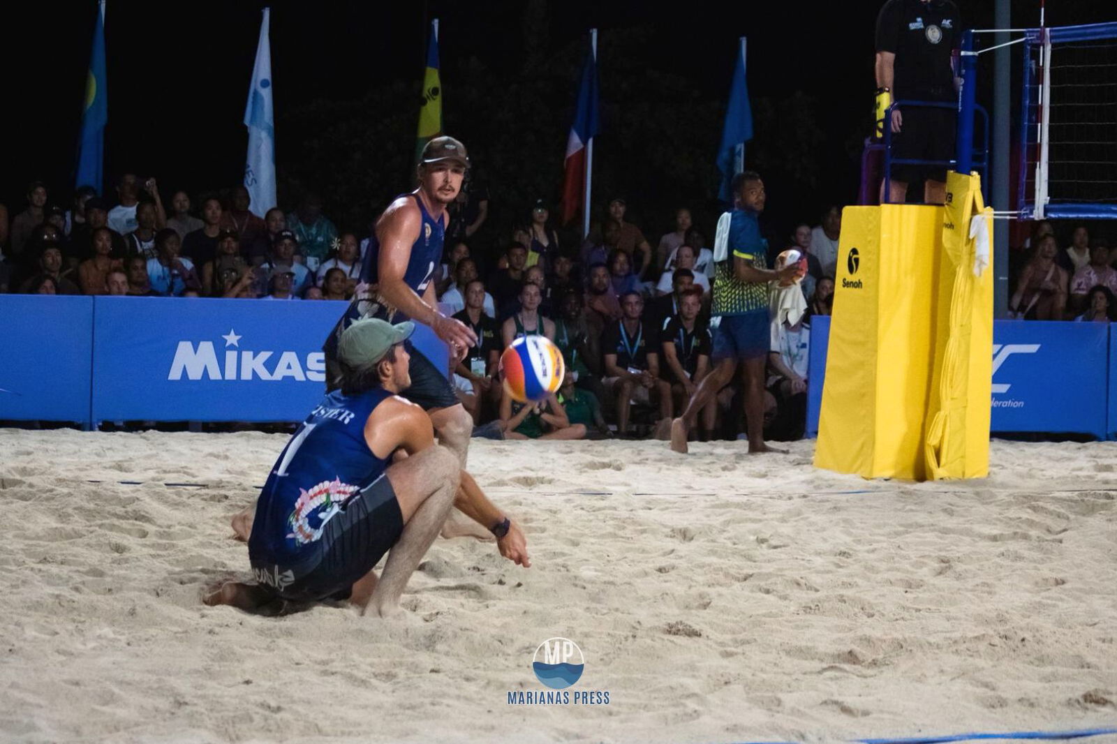 NMI’s Logan Mister bends down to receive a serve from Australia, while teammate Andrew Johnson looks on during their gold medal game last Tuesday night at the Long Island Beach in Palau.Marianas Press photo