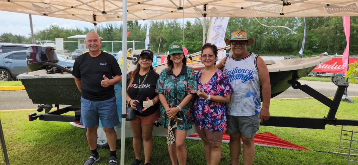 Saipan Mayor Ramon “R.B.” Camacho, right, and Saipan International Fishing Association representatives pose for a photo the Saipan International Fishing Tournament festival on July 13, 2025, at Smiling Cove Marina. Also pictured is the boat that raffle participants had the opportunity to win.