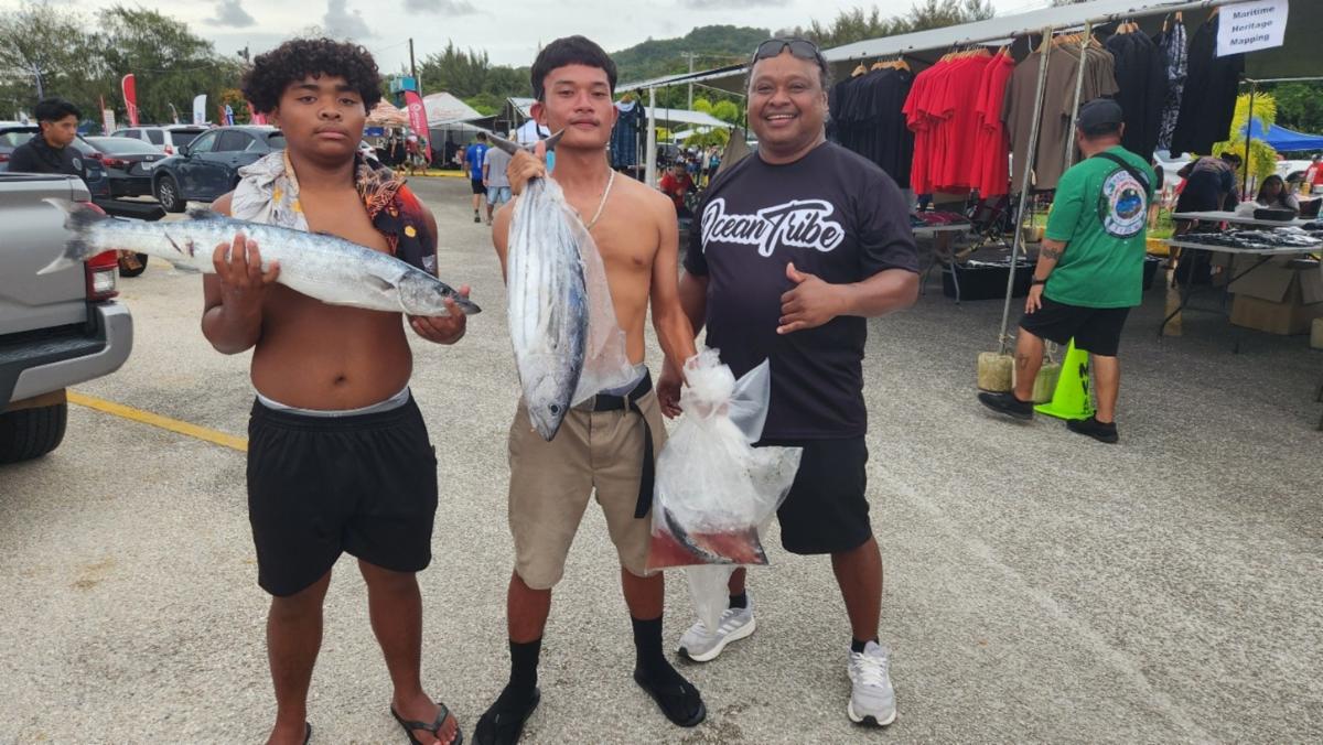 A young fisherman, center, displays his catch with family at the 41st Annual Saipan International Fishing Tournament festival on July 13, 2025, at Smiling Cove Marina.