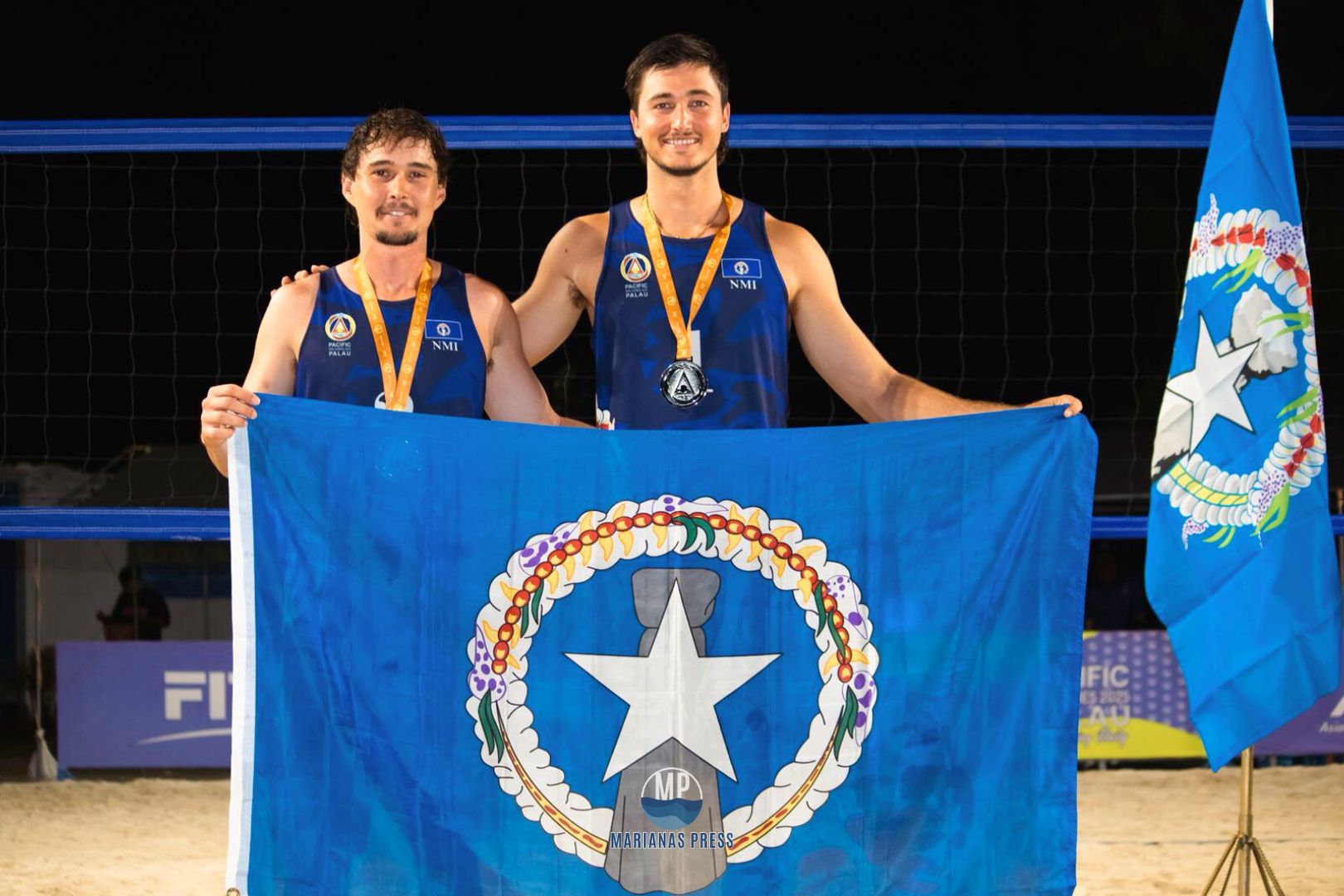 NMI beach volleyball players Logan Mister and Andrew Johnson pose for a photo with their silver medals and the CNMI flag at the 2025 Pacific Mini Games in Koror, Palau.Marianas Press photo