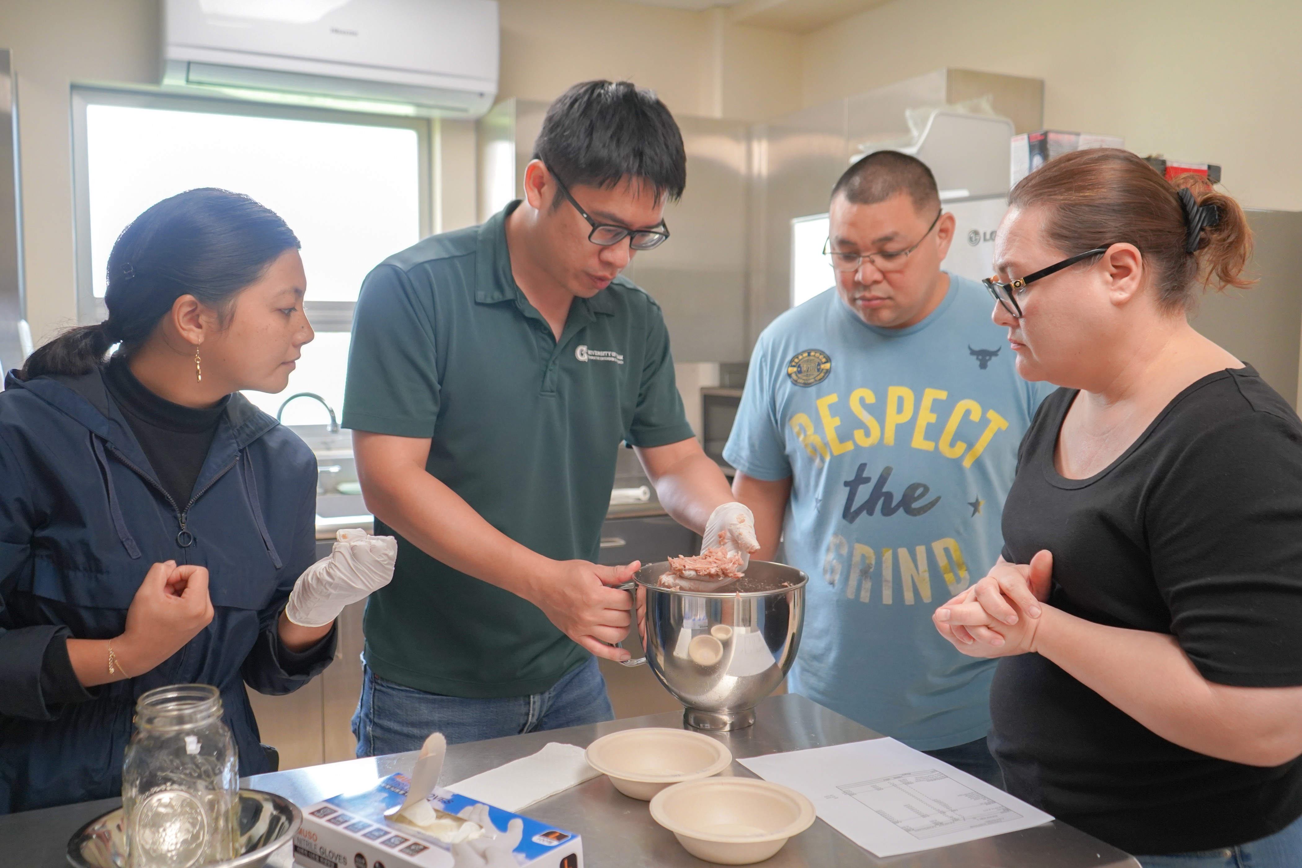 University of Guam Land Grant meat scientist Dr. Jeng-Hung Liu inspects the consistency of pork to be turned into sausage during a meat processing workshop held in August 2023 at UOG. From left, Rita Barcinas, Liu, Marvin Crisostomo, and Christina Crisostomo.