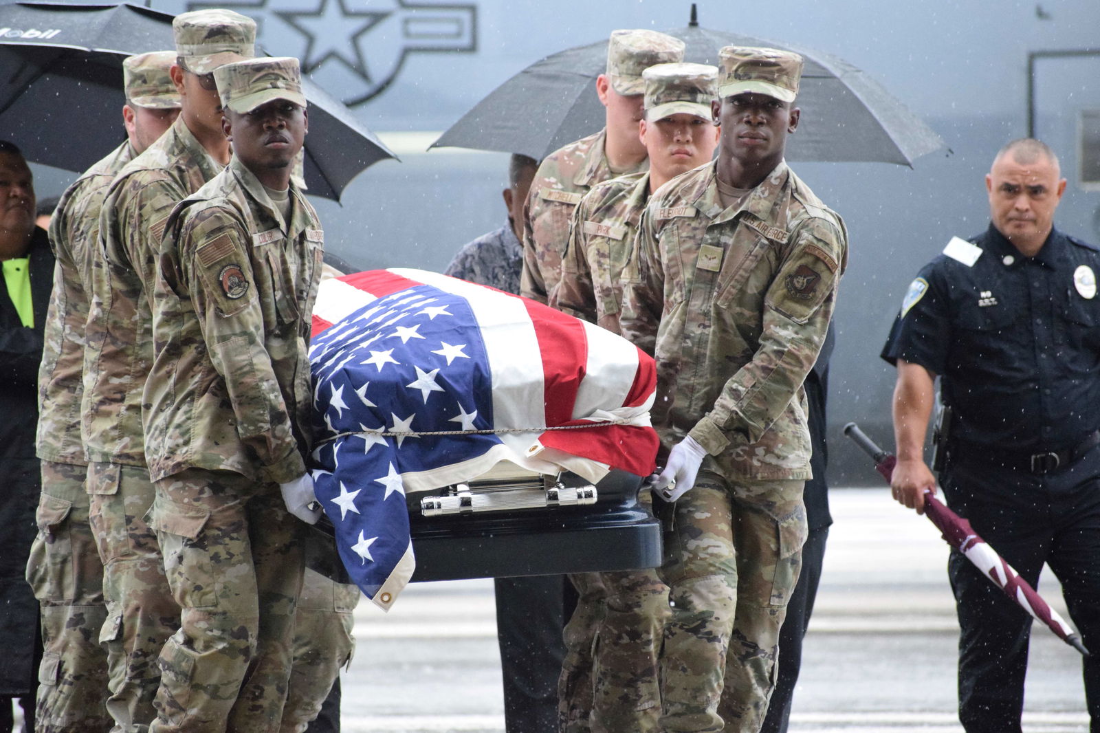 U.S. service members carrying the late governors' casket approach the hangar